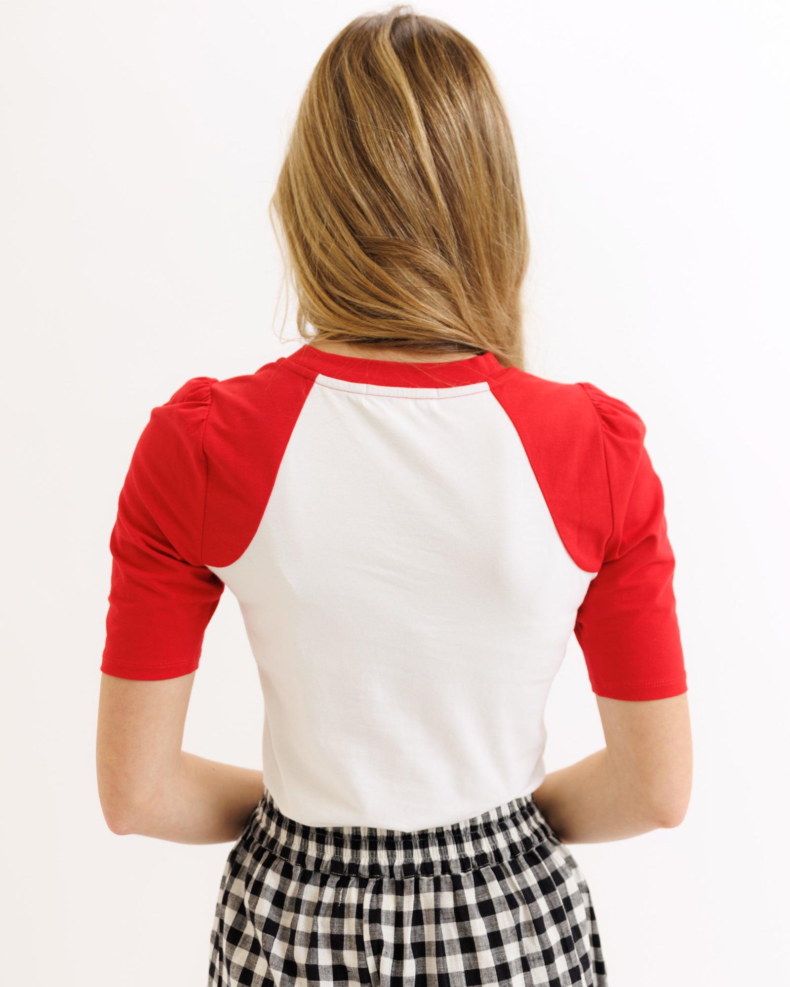 Person wearing a red and white shirt with checkered pants on a white background