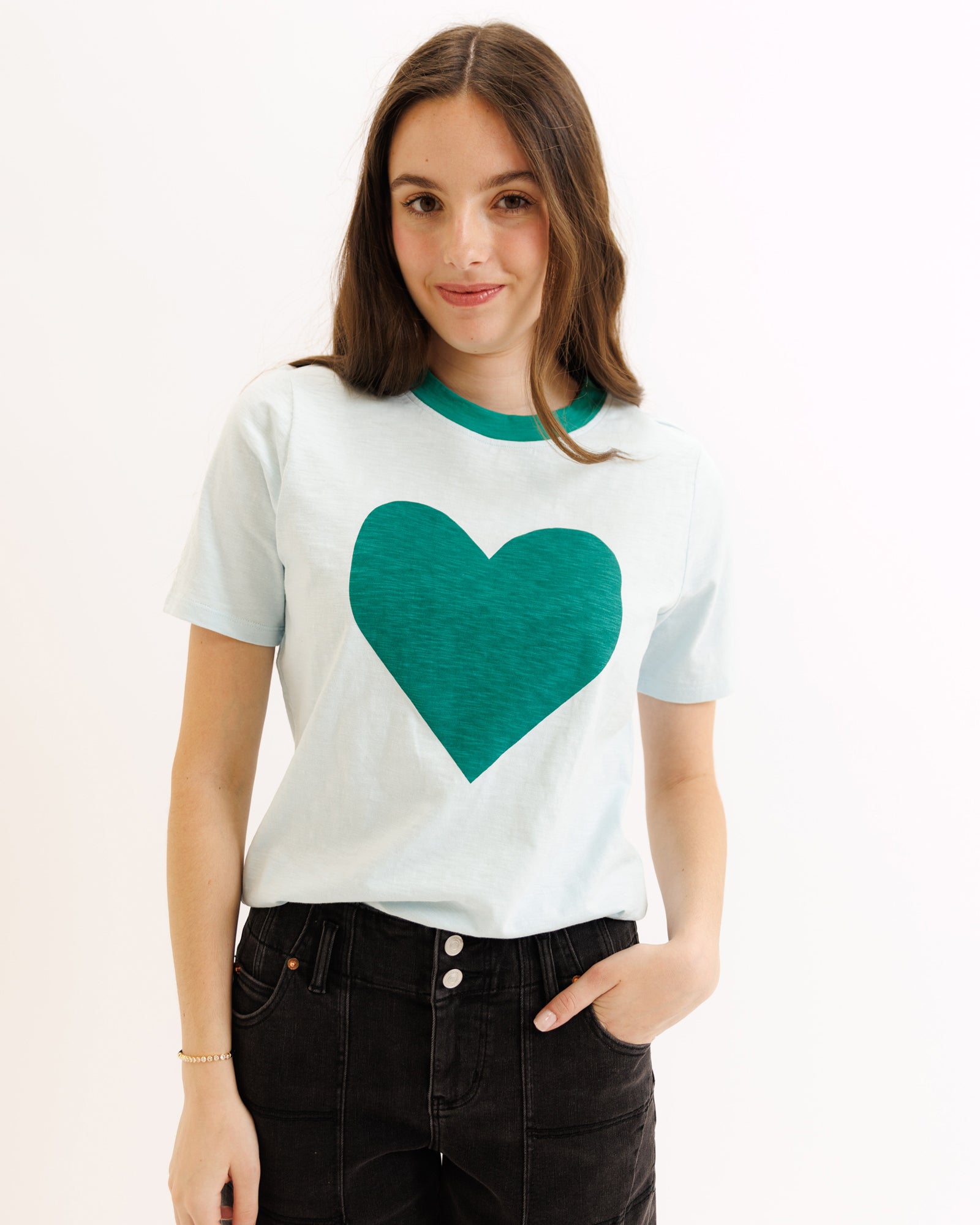 Woman wearing a white t-shirt with a green heart design on a white background