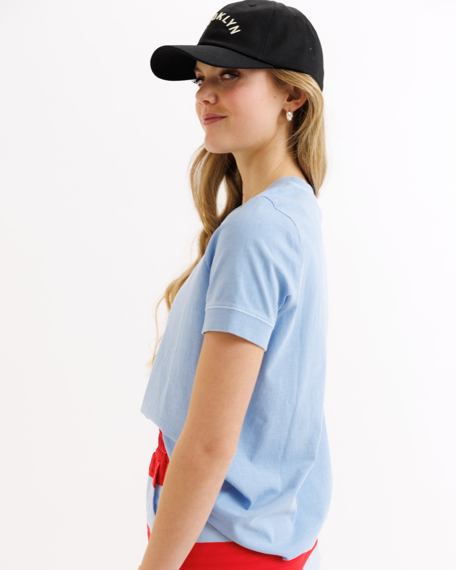 Woman wearing a black cap and light blue shirt on a white background
