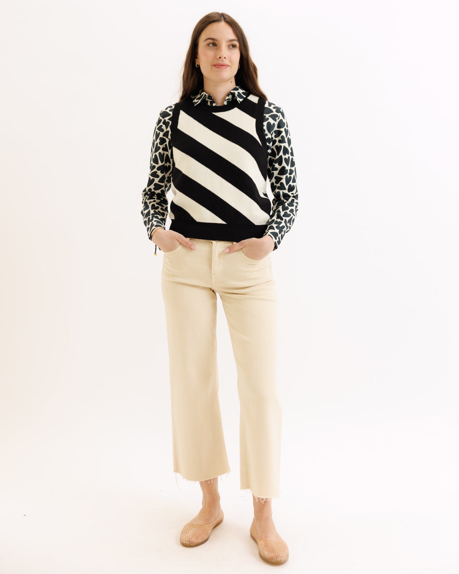 Woman wearing a black and white striped sweater with leopard print collar and beige pants on a white background