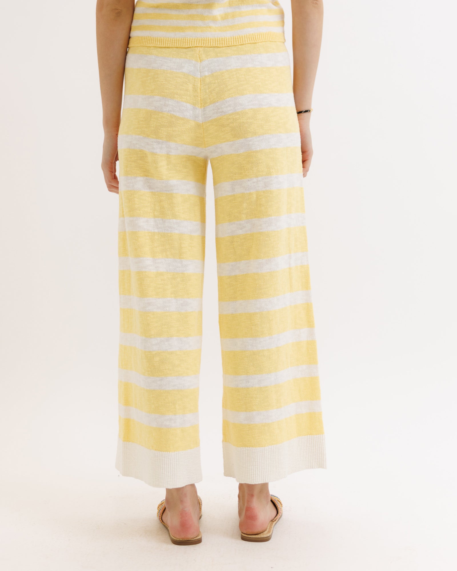 Yellow and white striped pants worn by a person on a light pink background