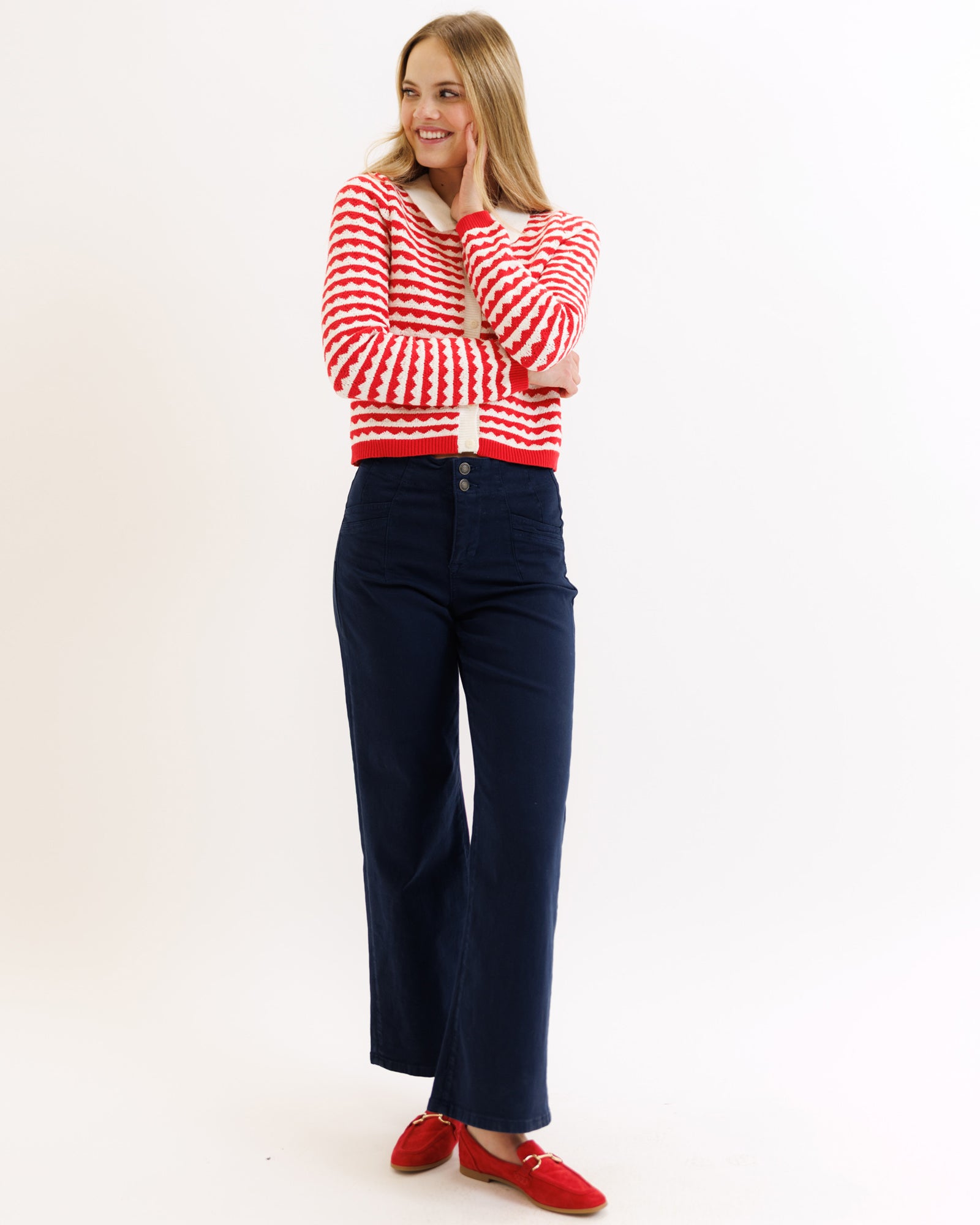 Woman wearing a red and white striped sweater and navy pants on a white background