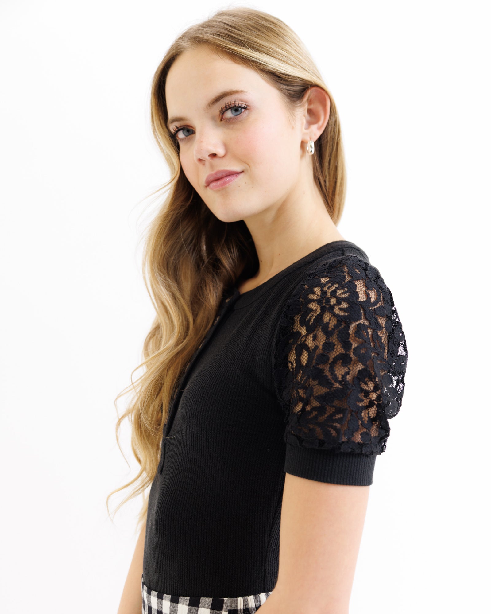 Woman wearing a black top with lace sleeves on a white background