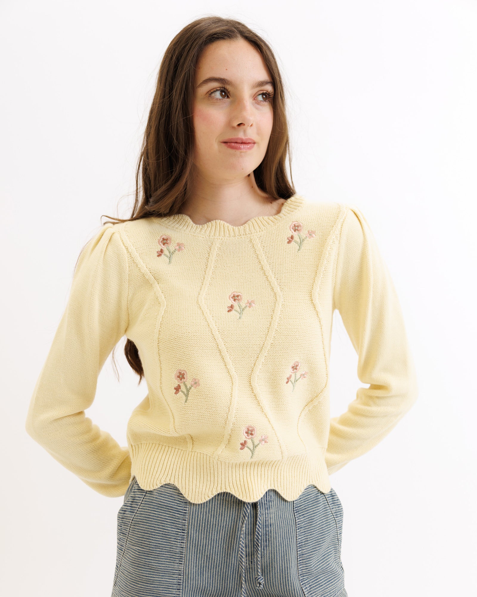 Woman wearing a yellow embroidered sweater against a white background