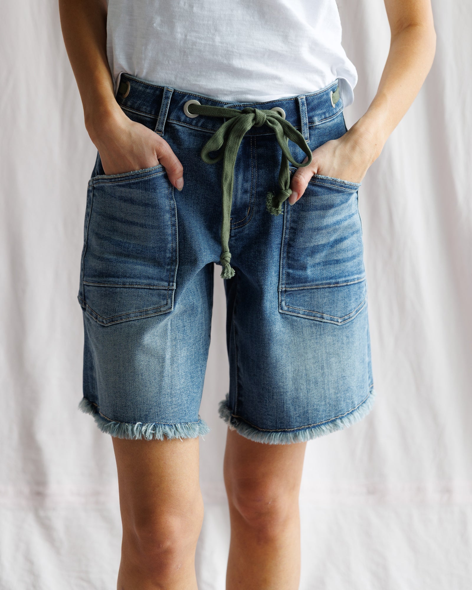 Person wearing blue denim shorts with a white background