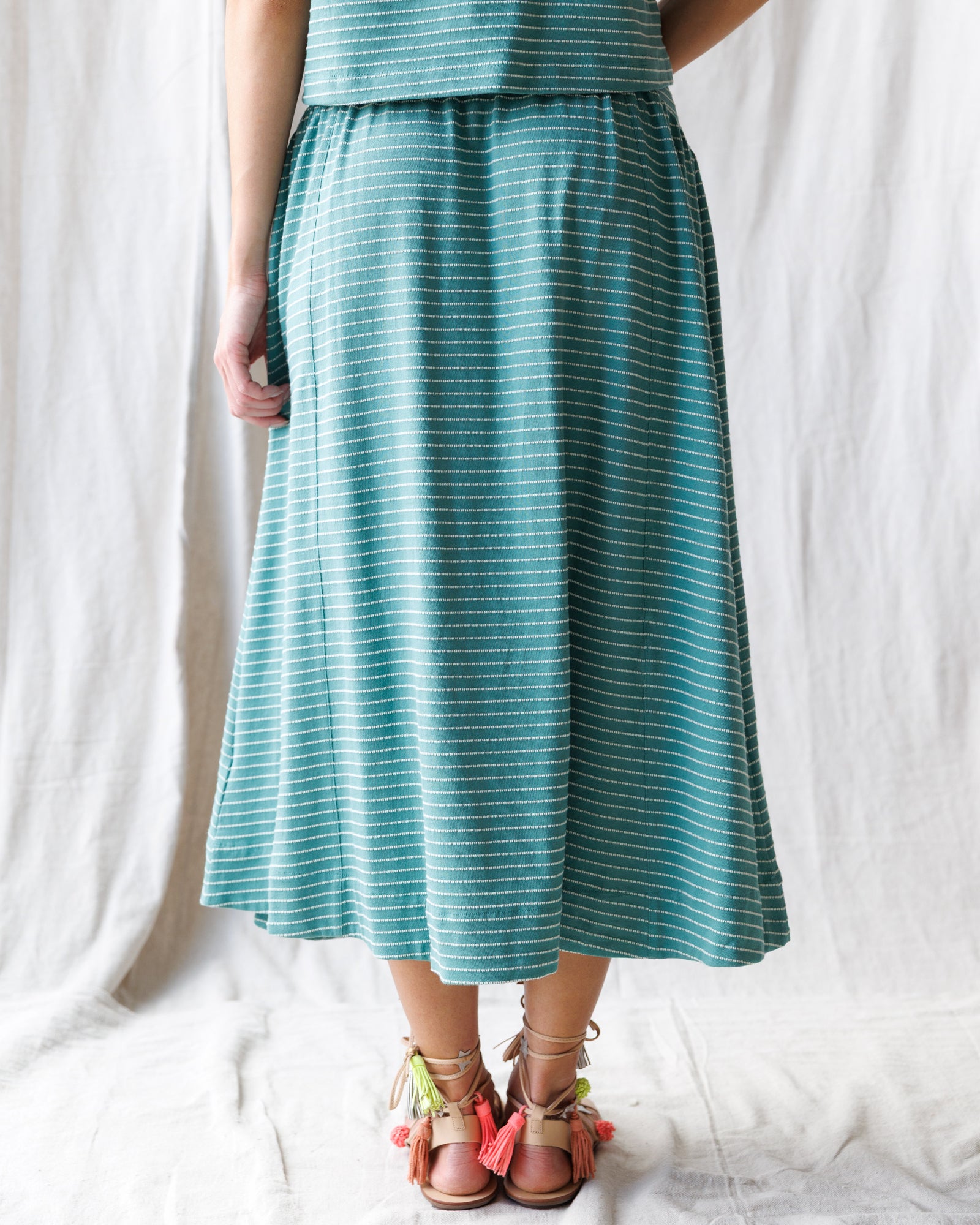 Person wearing a teal striped dress on a white background