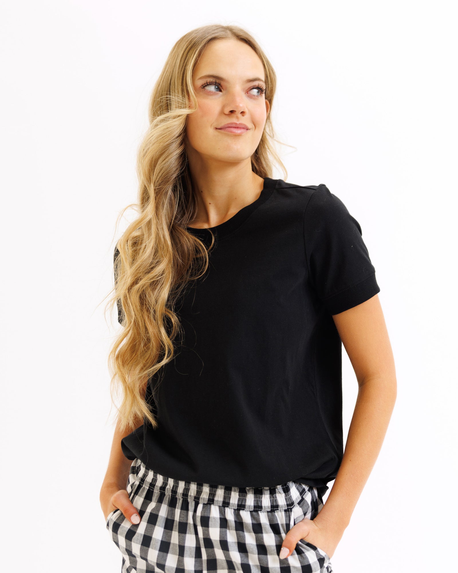 Woman wearing a black t-shirt and checkered pants on a white background
