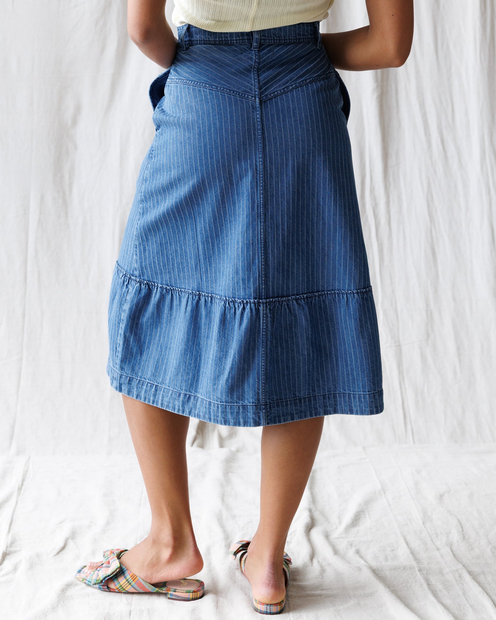 Person wearing a blue denim skirt on a white background