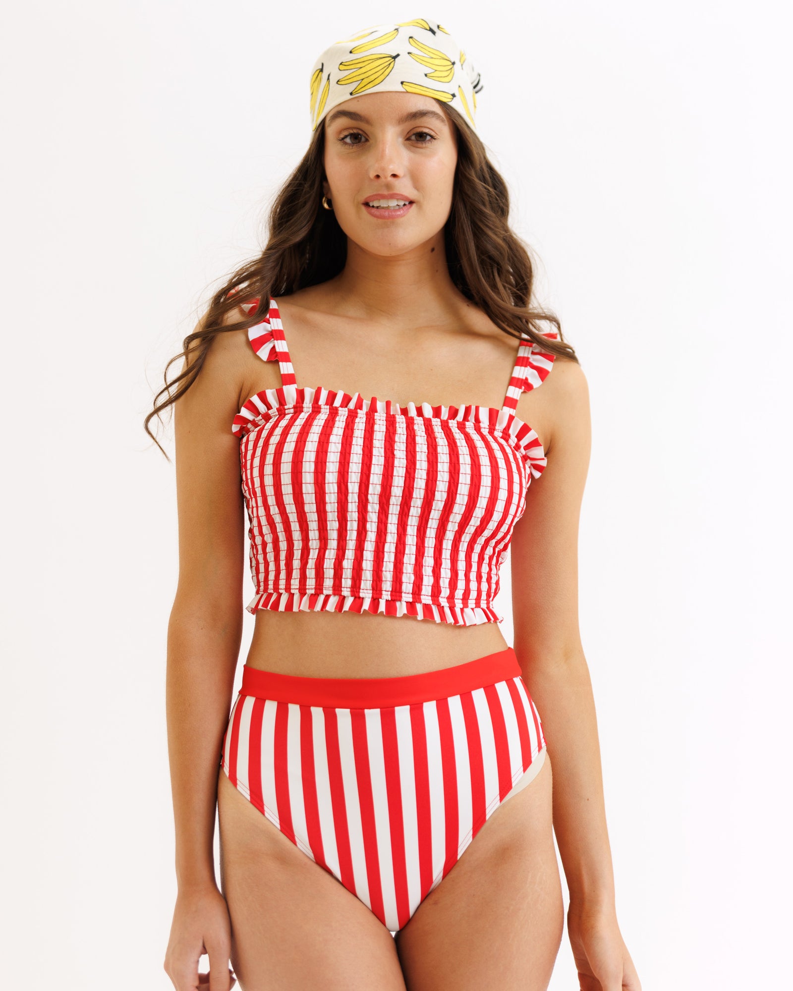 Woman wearing a red and white striped bikini with a matching headband on a white background