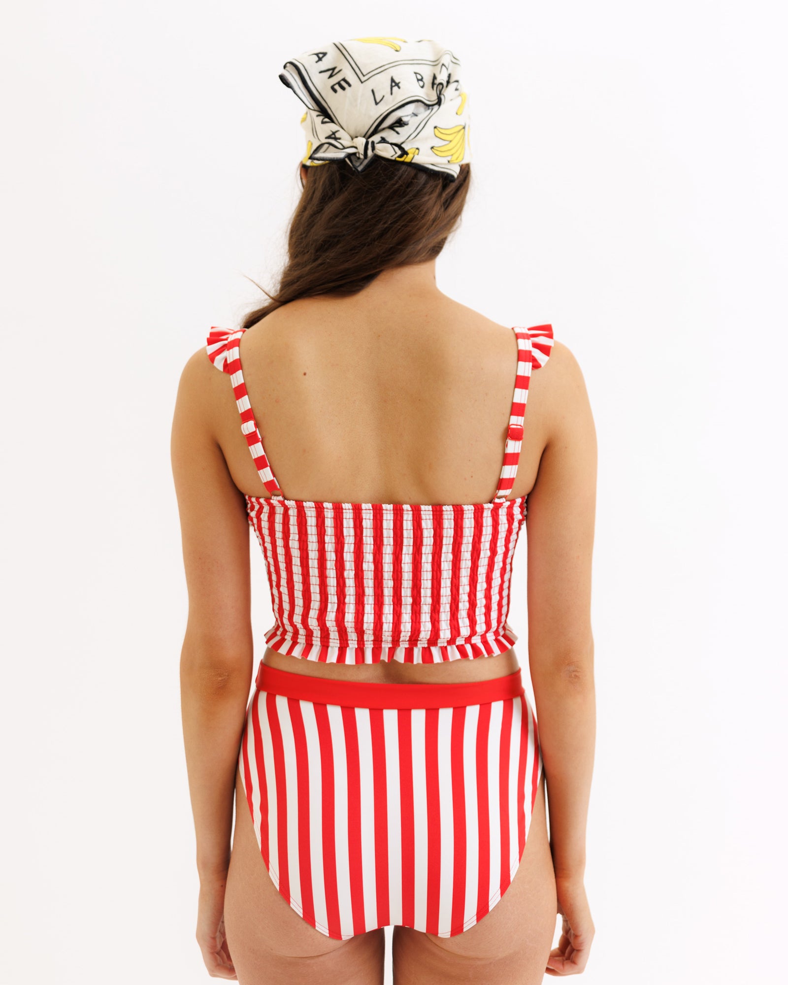 Woman wearing a red and white striped swimsuit with a headscarf on a white background