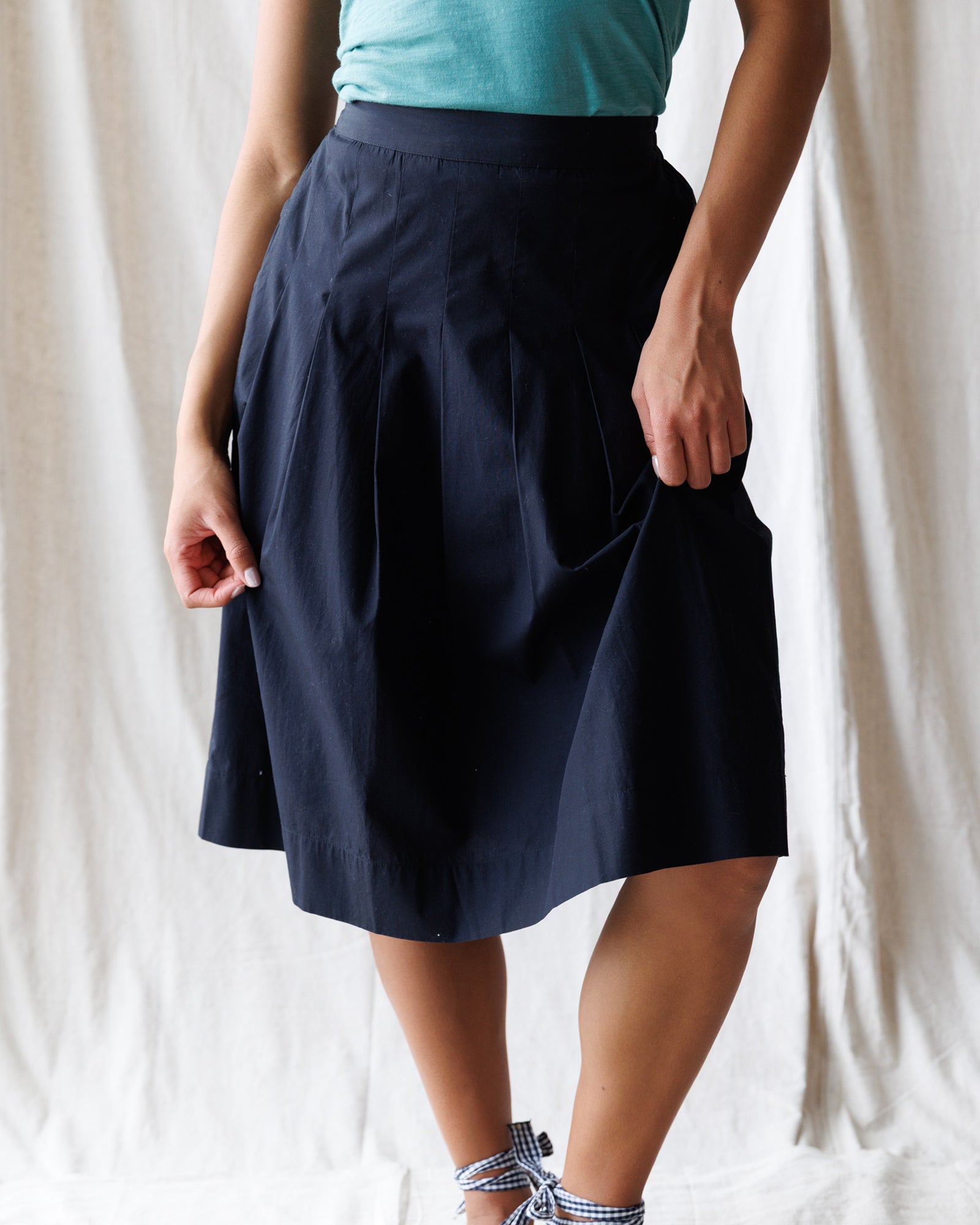 Person wearing a navy blue skirt with a white background