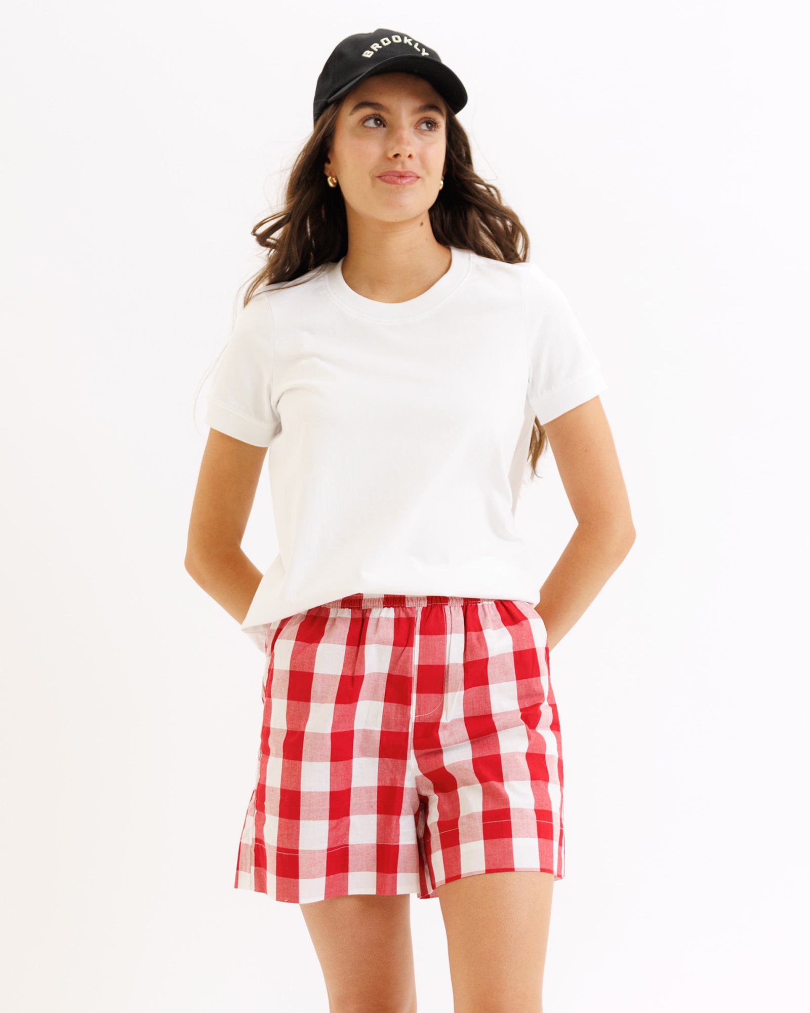 Woman wearing a white t-shirt and red checkered shorts on a white background