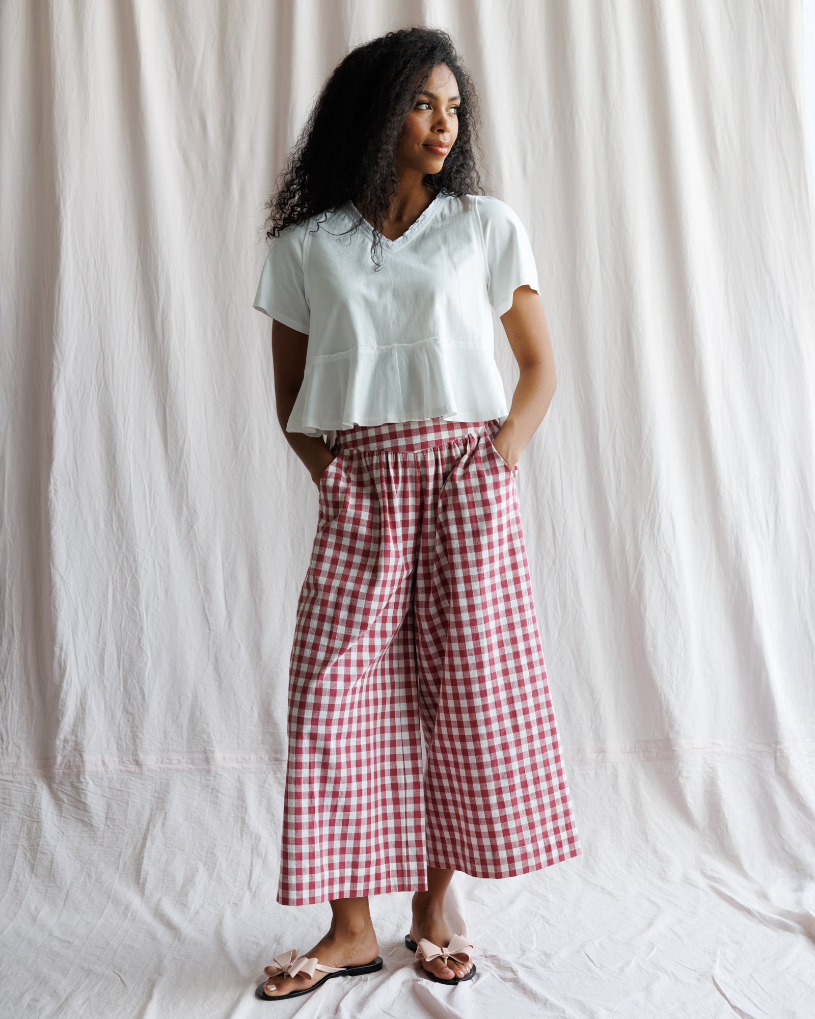 Woman wearing a light blue top and red checkered pants against a white background