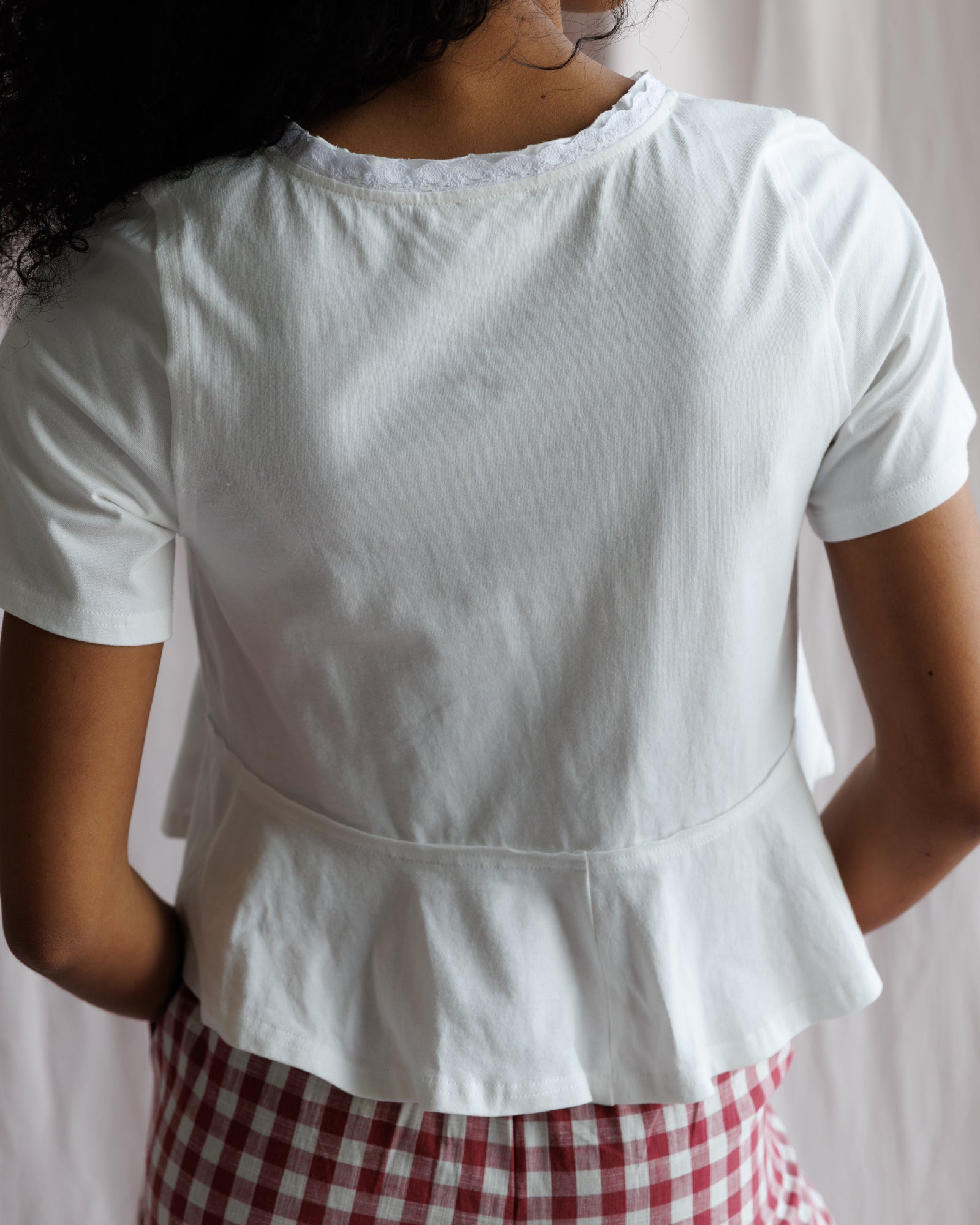 Person wearing a white top with a plain background