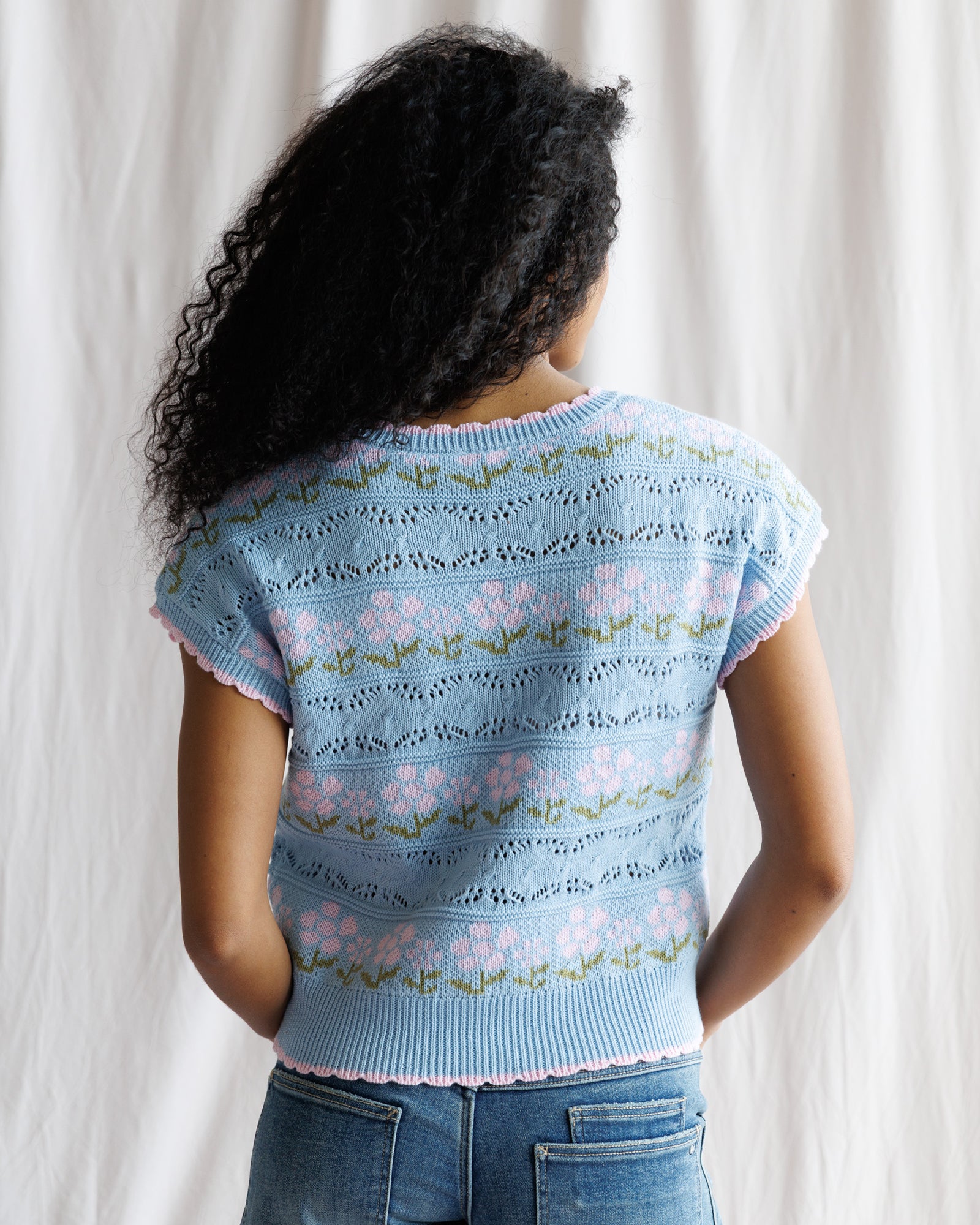 Person wearing a light blue floral-patterned sweater against a white background