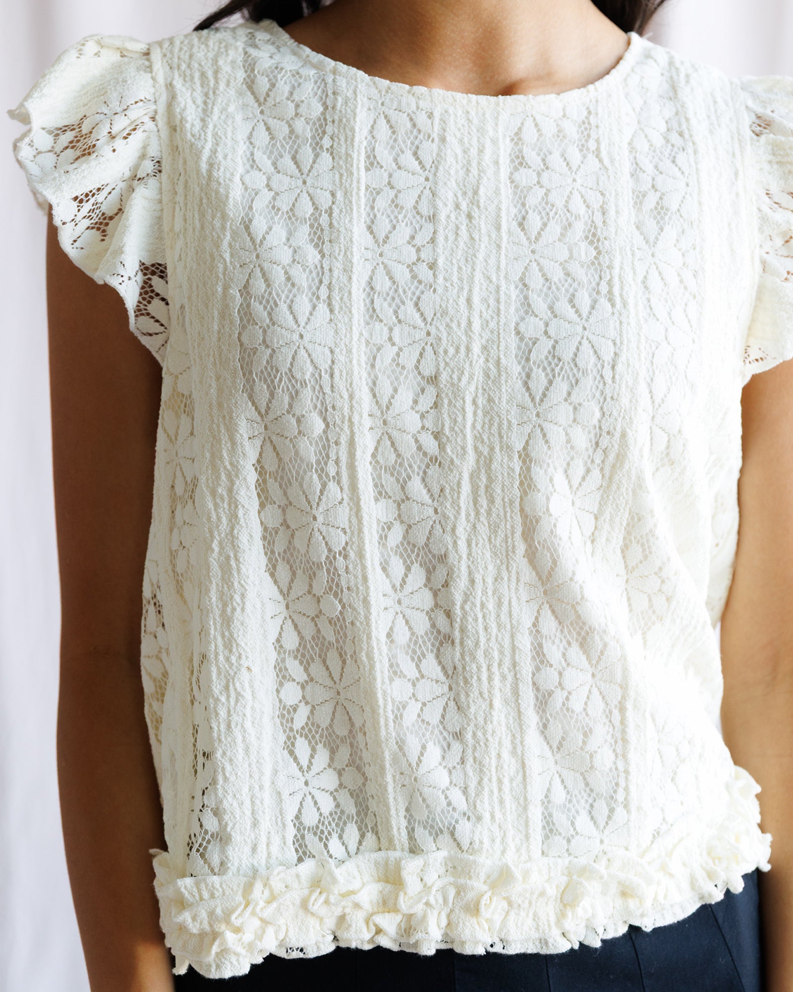 White lace top worn by a person on a white background