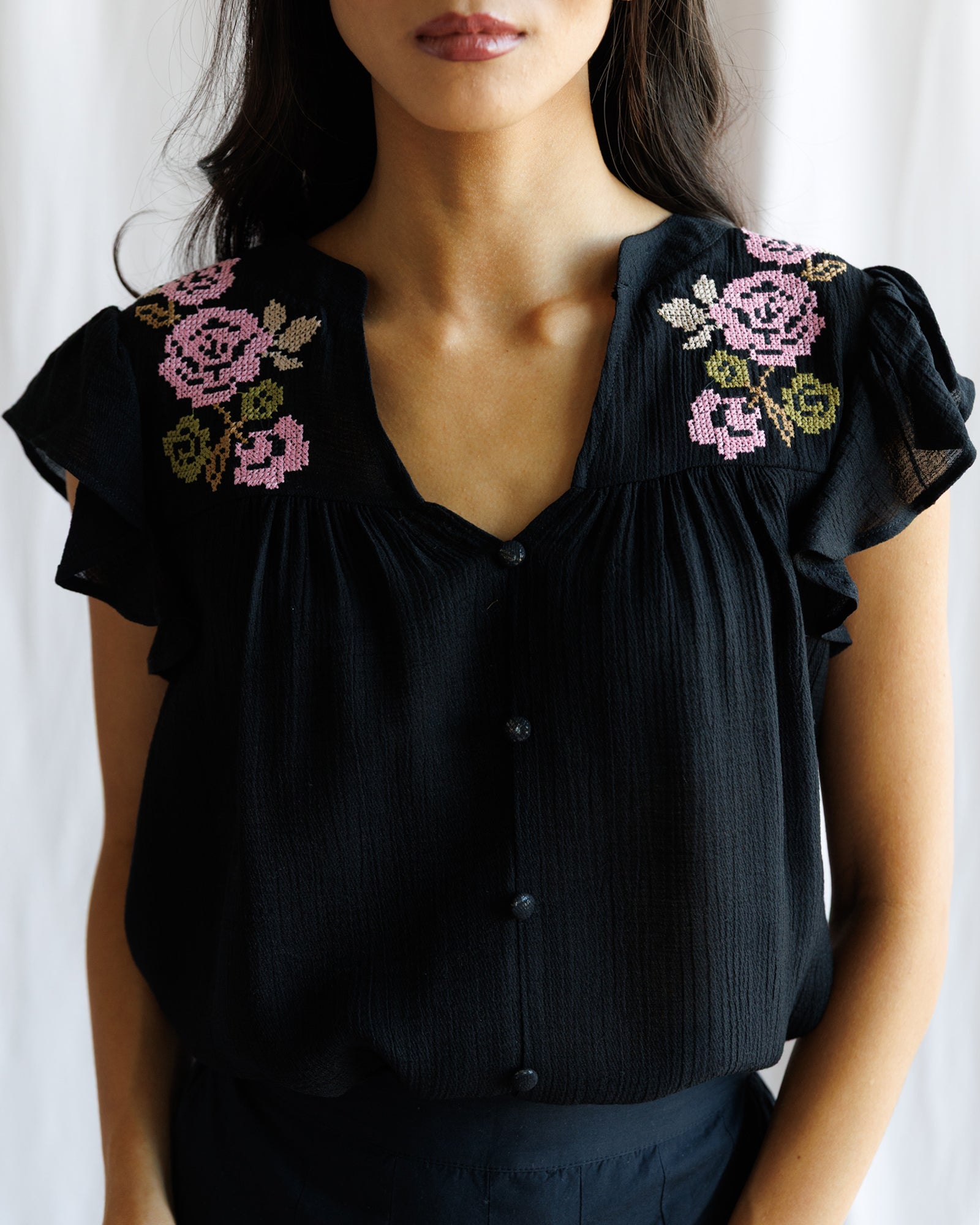Black blouse with floral embroidery on a white background
