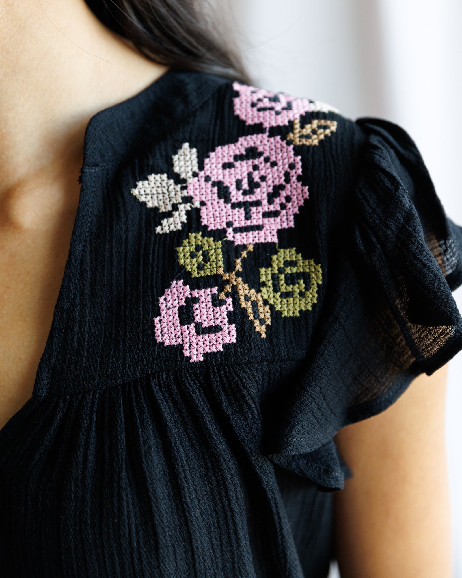 Black dress with pink floral embroidery on a blurred background