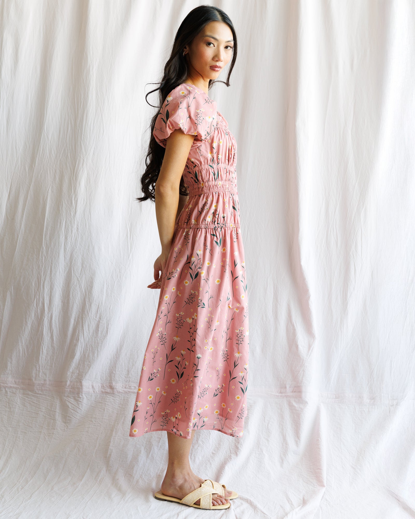 Woman wearing a pink floral dress against a white background