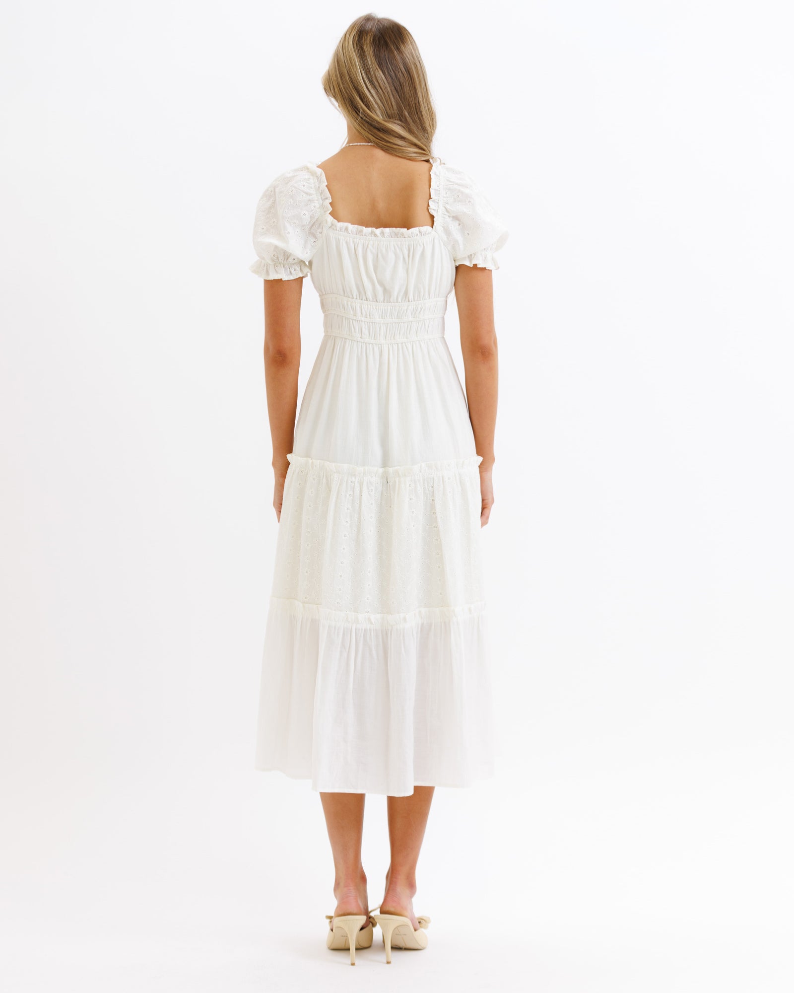 Woman wearing a white dress with puffed sleeves on a white background