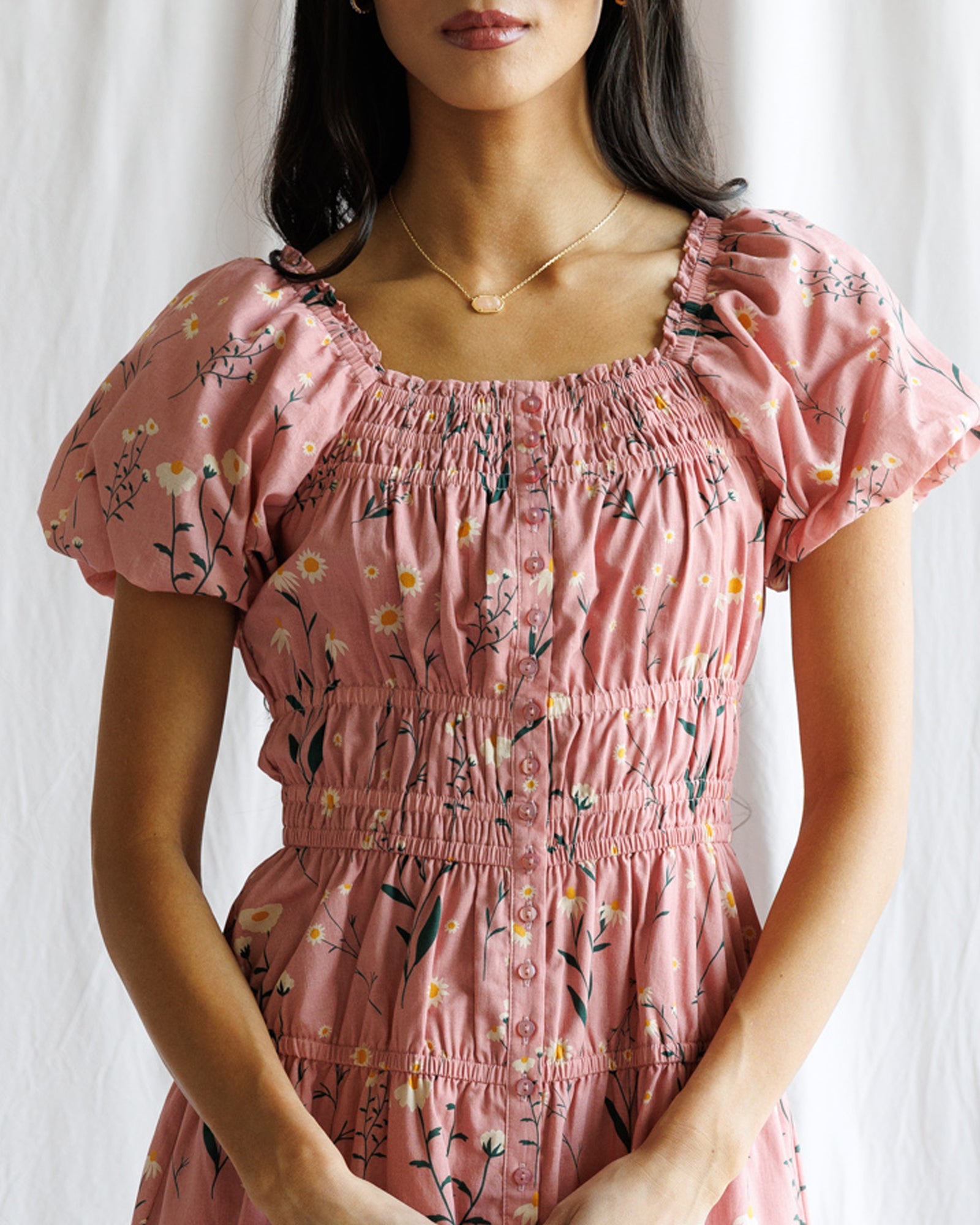Woman wearing a pink floral dress against a white background