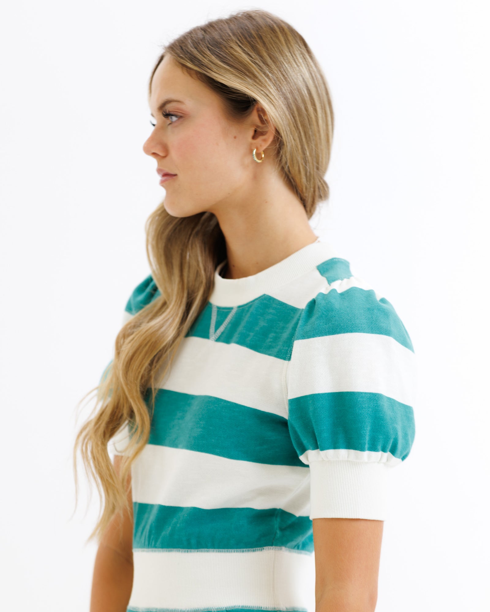 Woman wearing a teal and white striped shirt on a white background