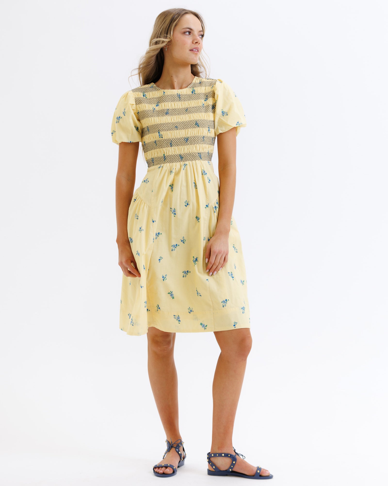 Woman wearing a yellow dress with a patterned bodice on a white background