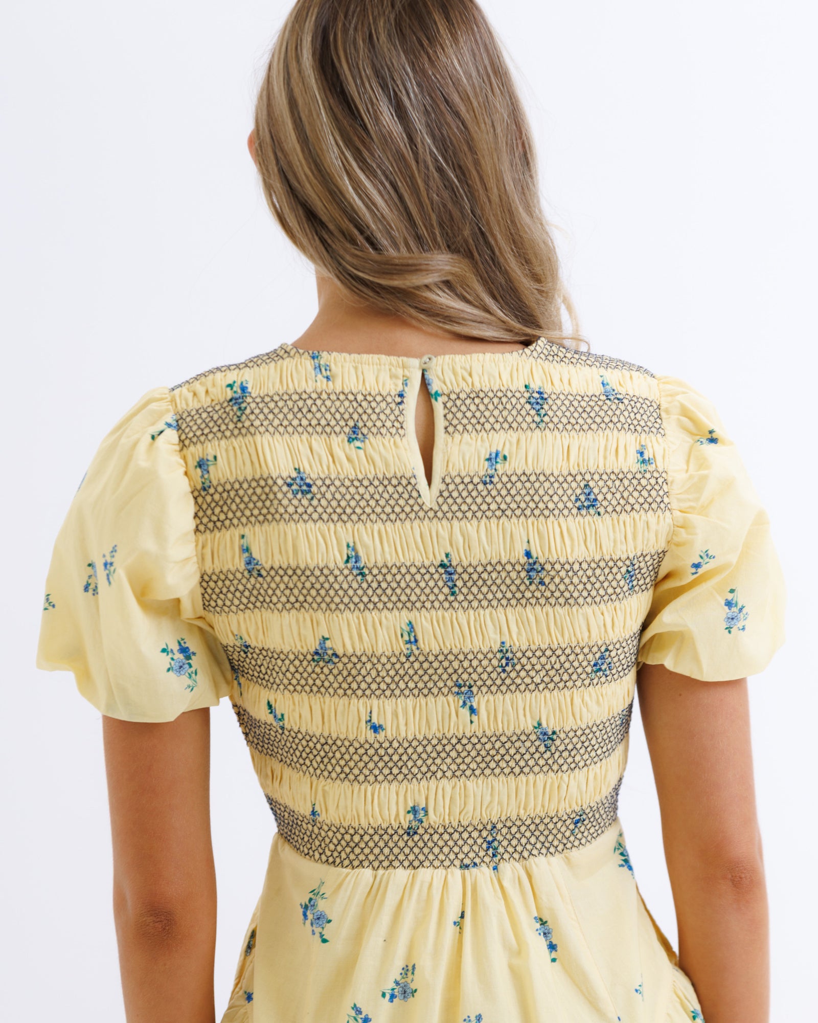 Yellow dress with floral pattern on a plain background