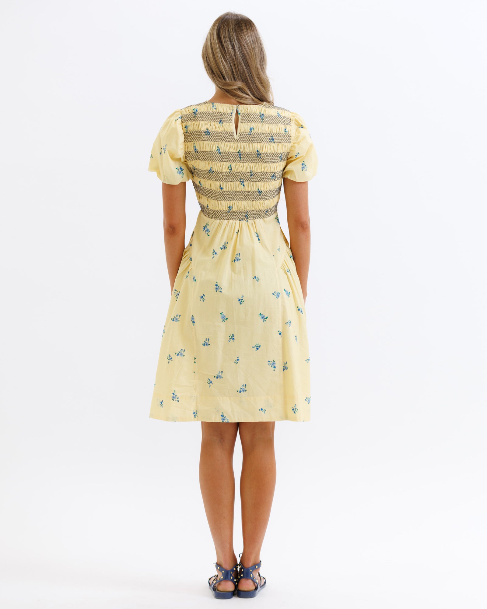 Woman wearing a yellow dress with a floral pattern on a white background
