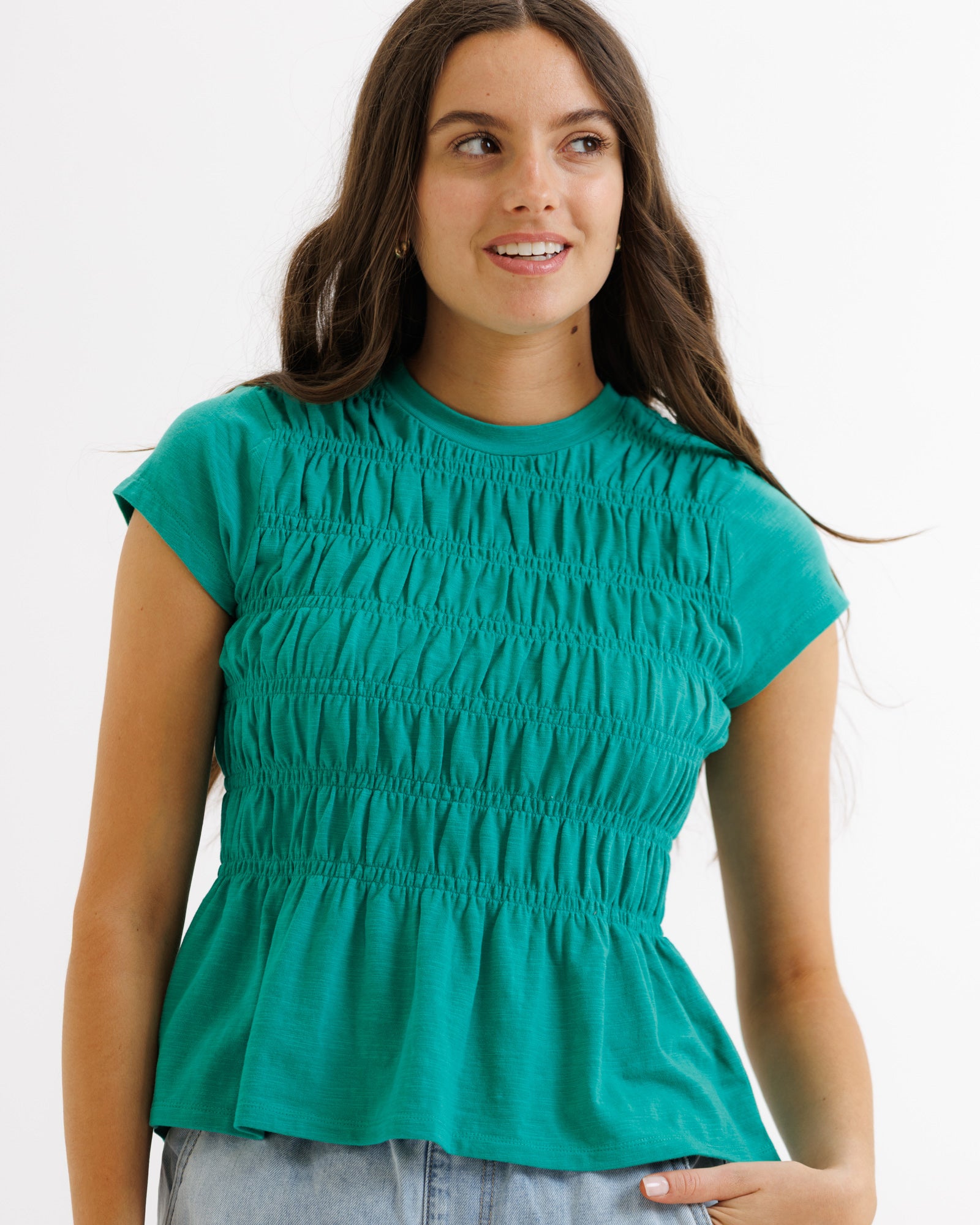 Woman wearing a teal top with a plain background