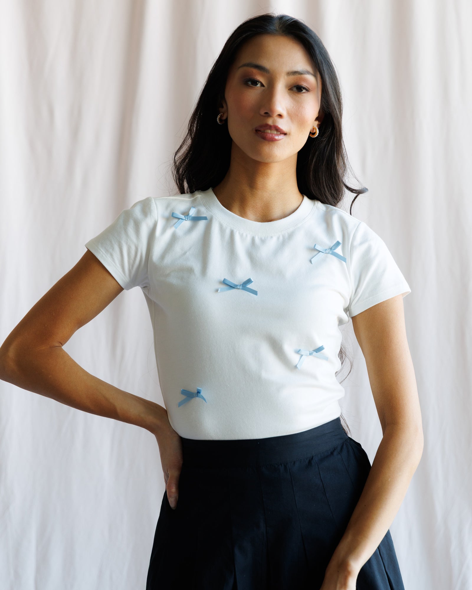 Woman wearing a white t-shirt with blue patterns against a plain background