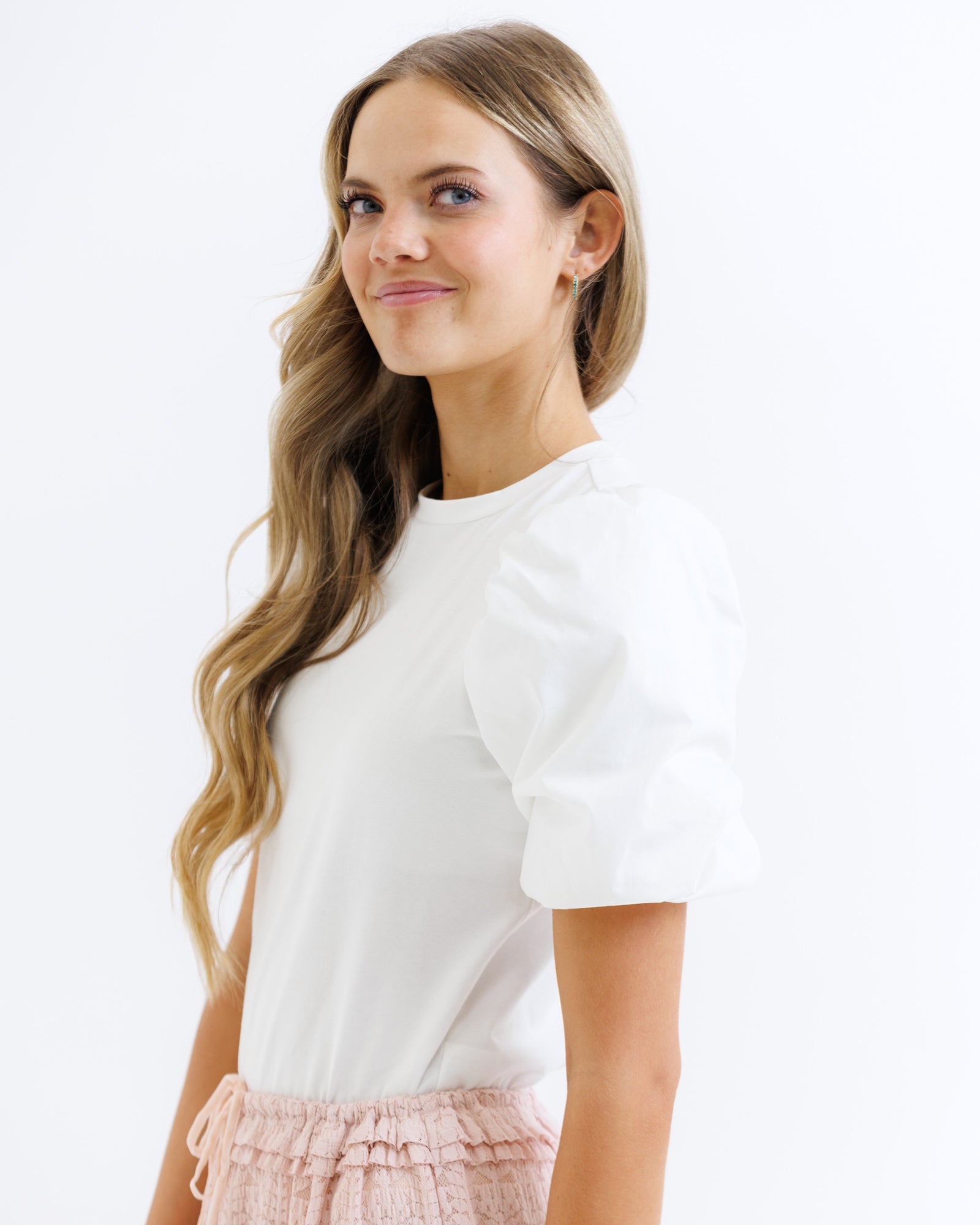 Woman wearing a white top with a plain background