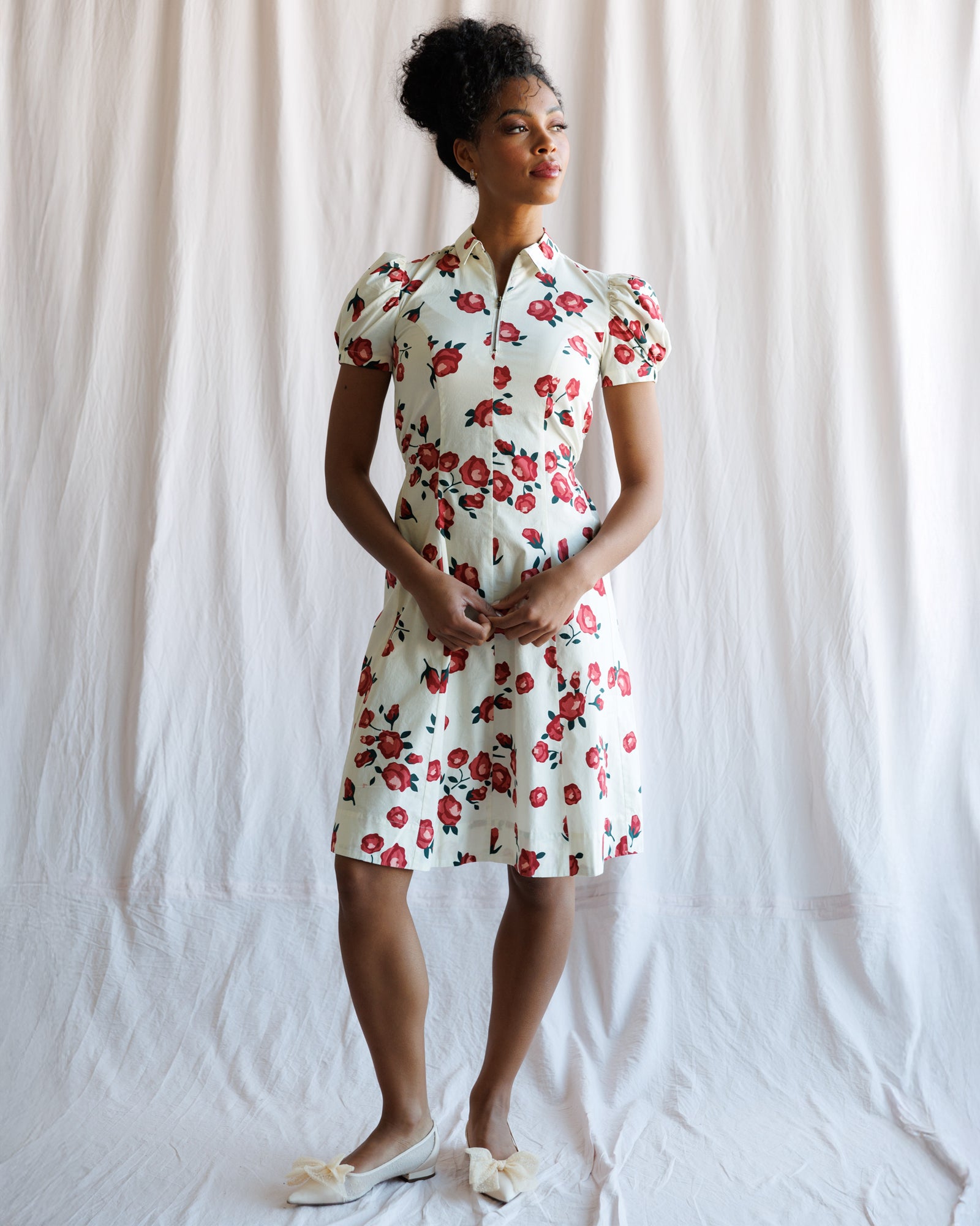 Woman wearing a floral dress standing against a white background