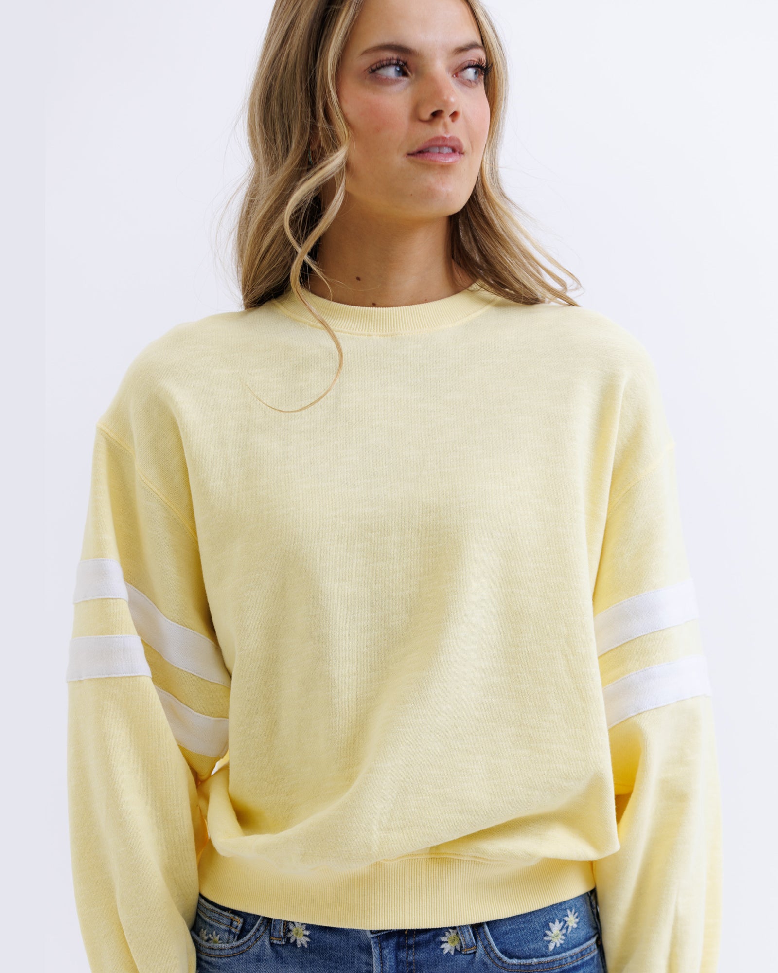 Woman wearing a yellow sweater with white stripes on a white background