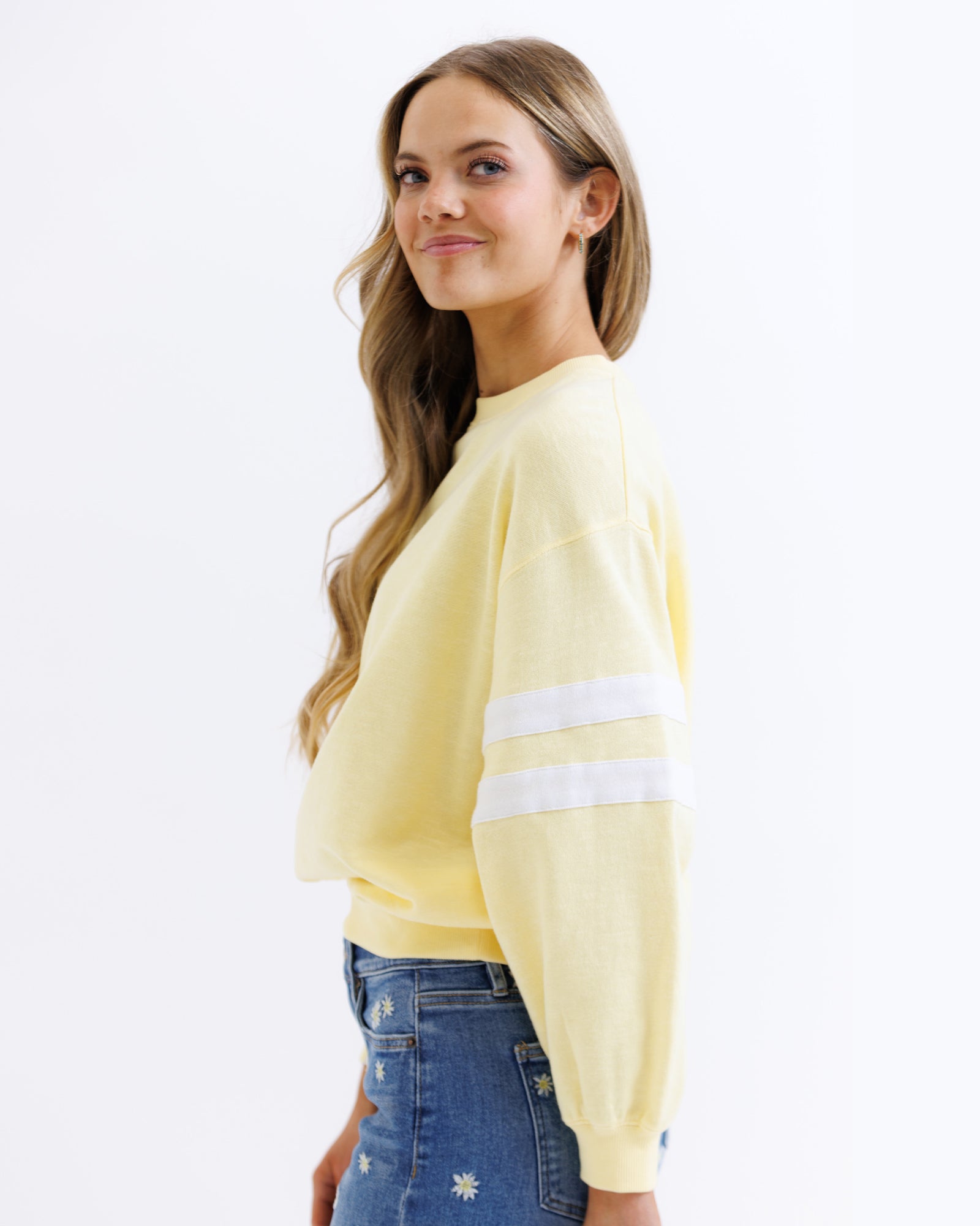 Woman wearing a yellow sweater with white stripes on a white background