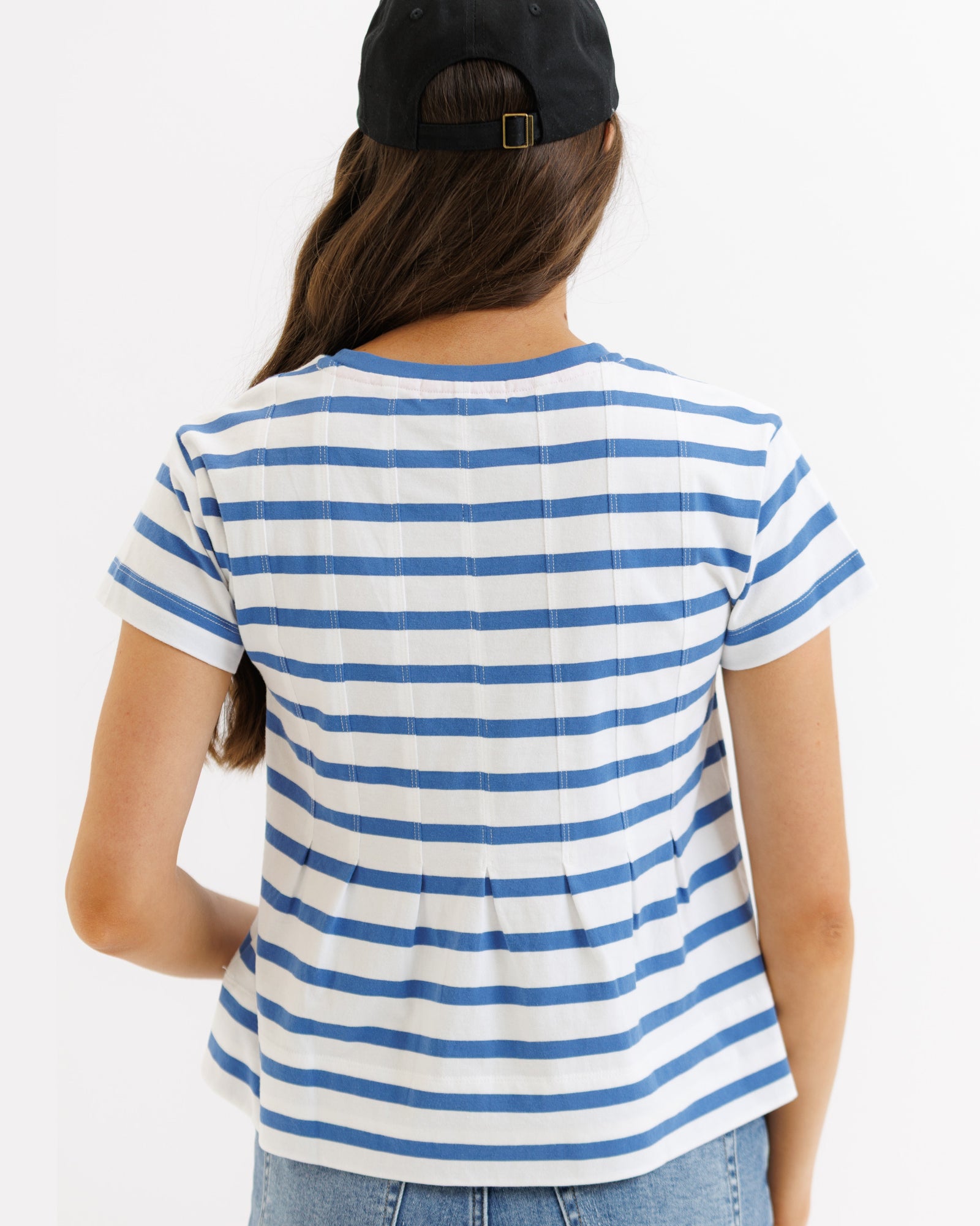 Person wearing a blue and white striped shirt with a black cap on a white background