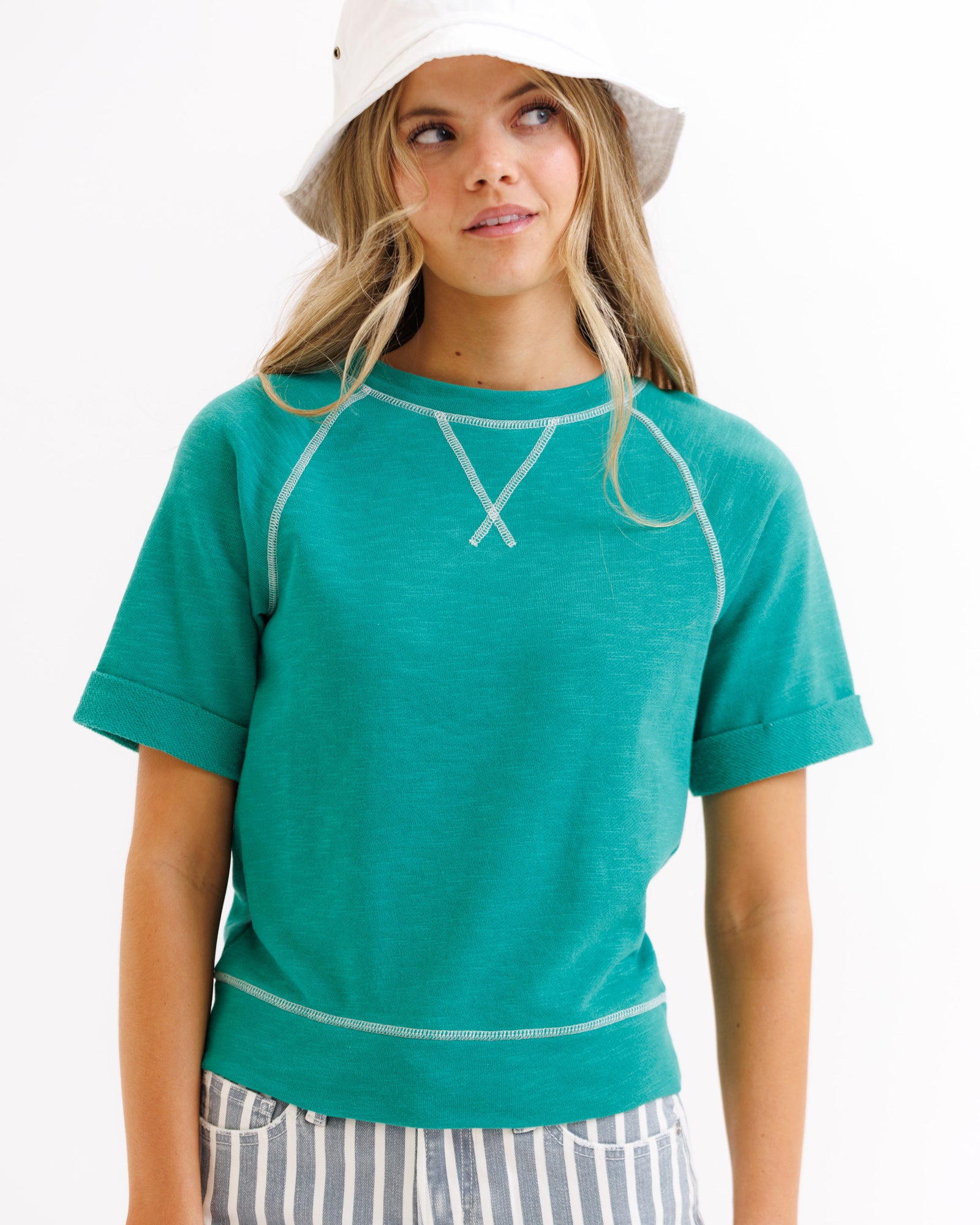 Woman wearing a teal t-shirt with white trim on a white background