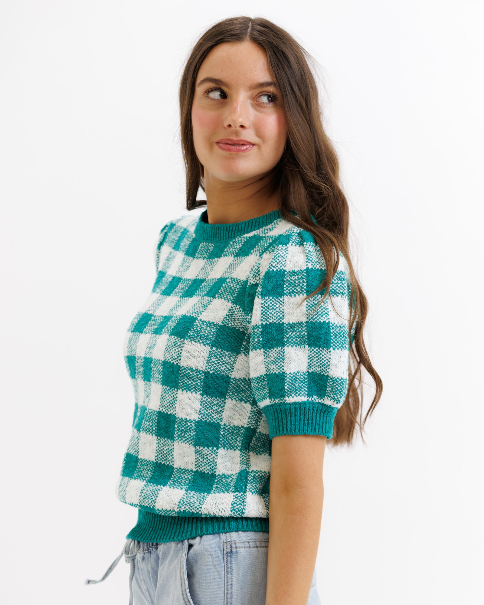 Woman wearing a green and white checkered sweater on a white background