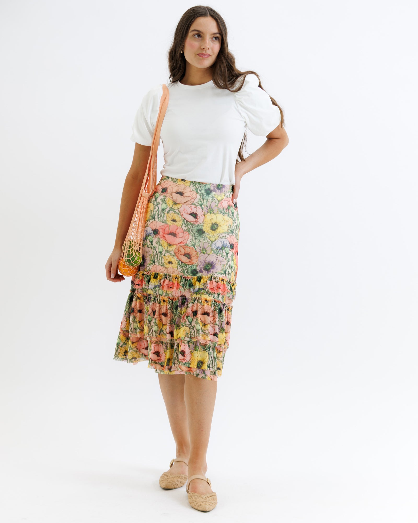 Woman wearing a floral skirt and white top on a white background