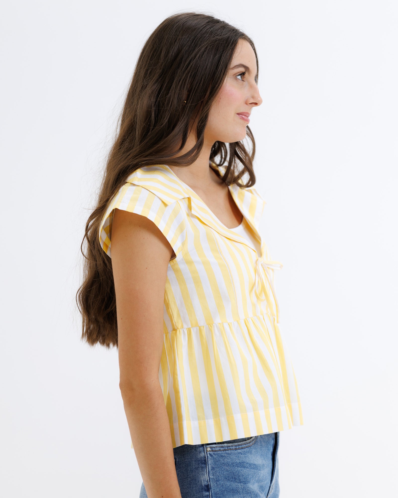 Woman wearing a yellow and white striped shirt against a plain background