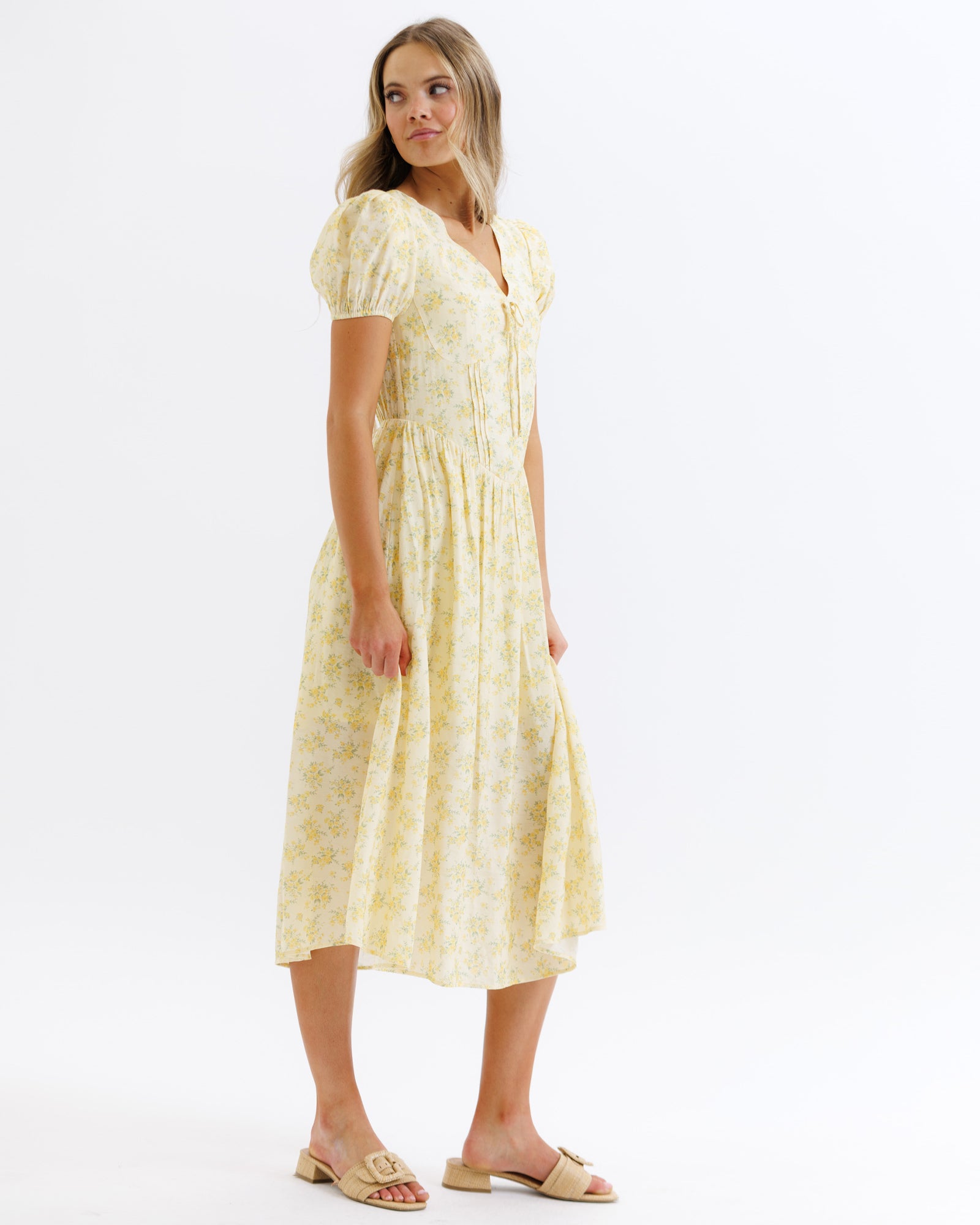 Woman wearing a yellow floral dress on a white background