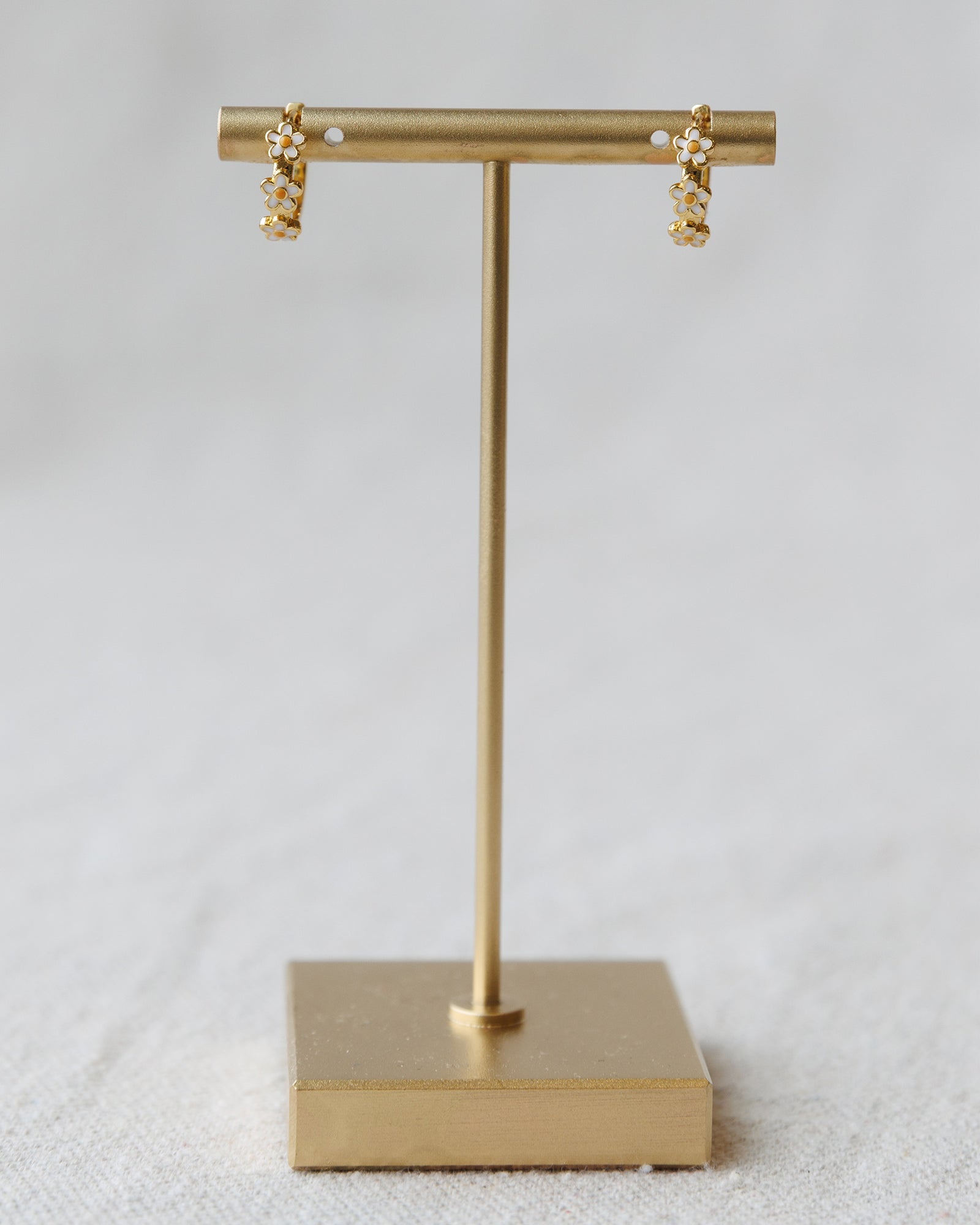 Gold earring stand with earrings on a light gray background