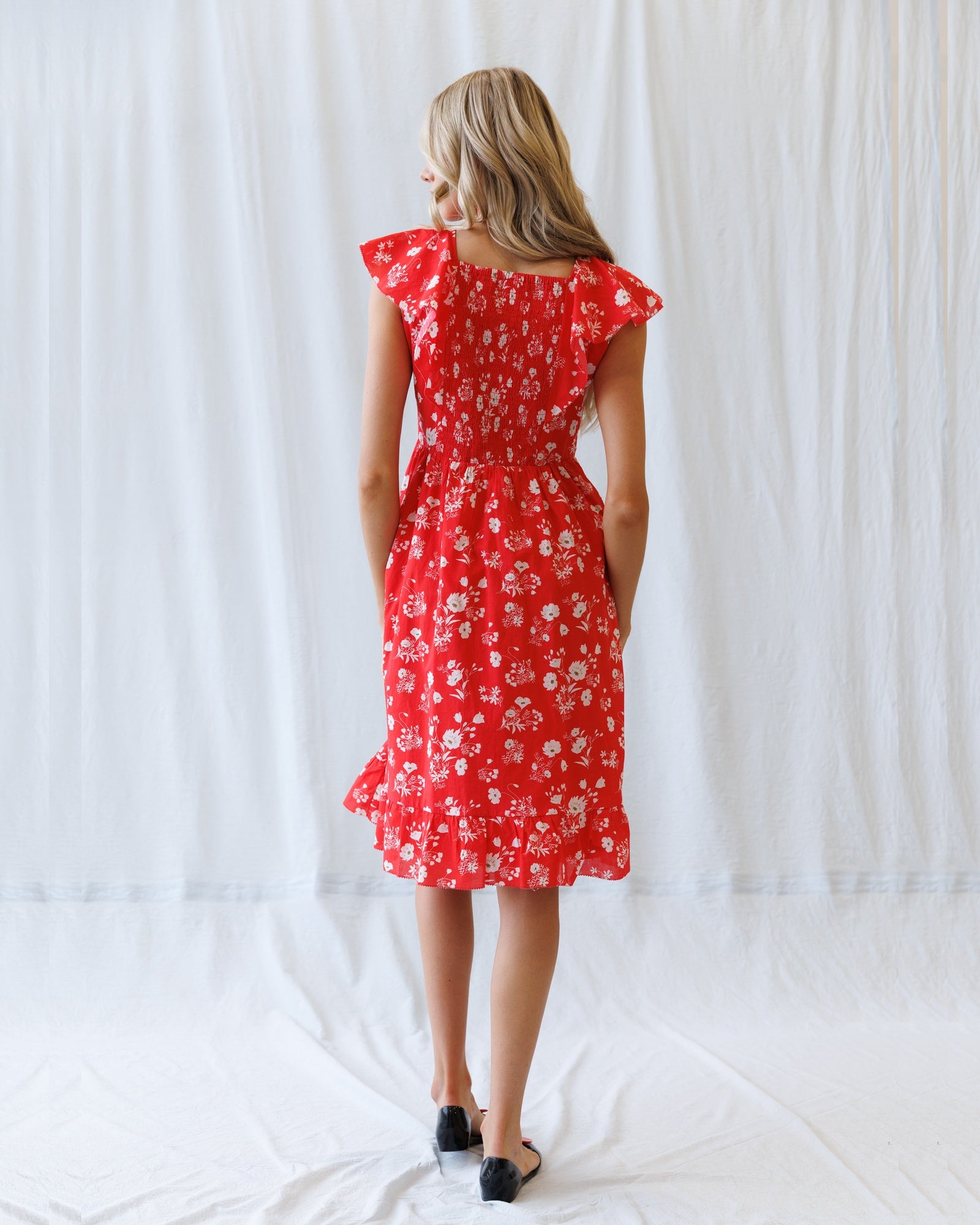 Woman wearing a red floral dress against a white background