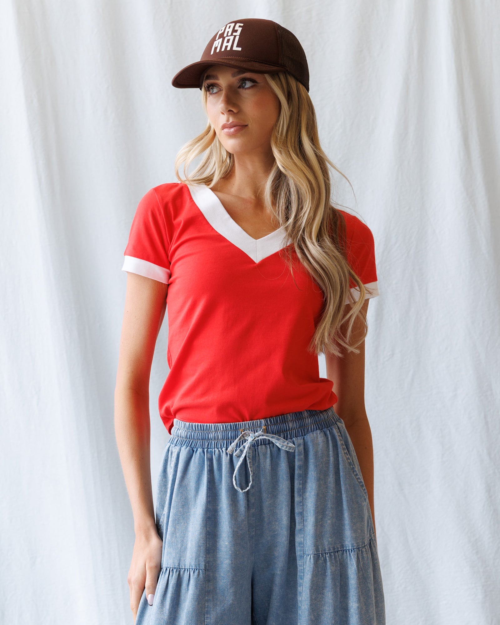 Woman wearing a red shirt and brown cap against a white background