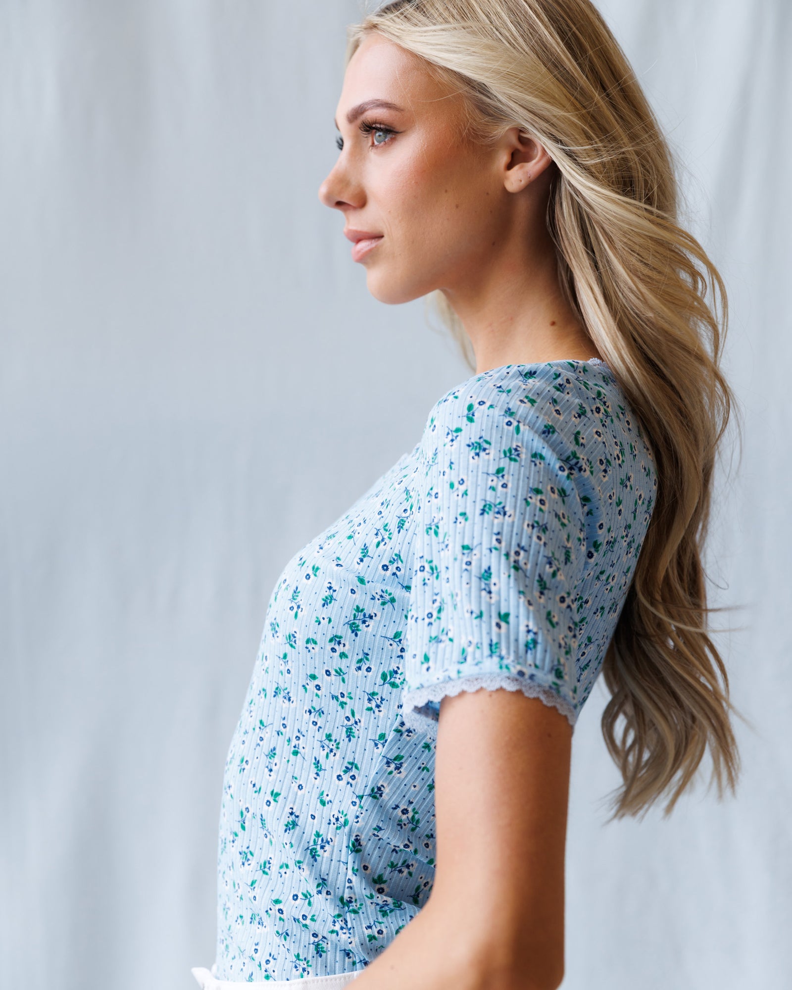 Woman wearing a blue floral dress against a light gray background