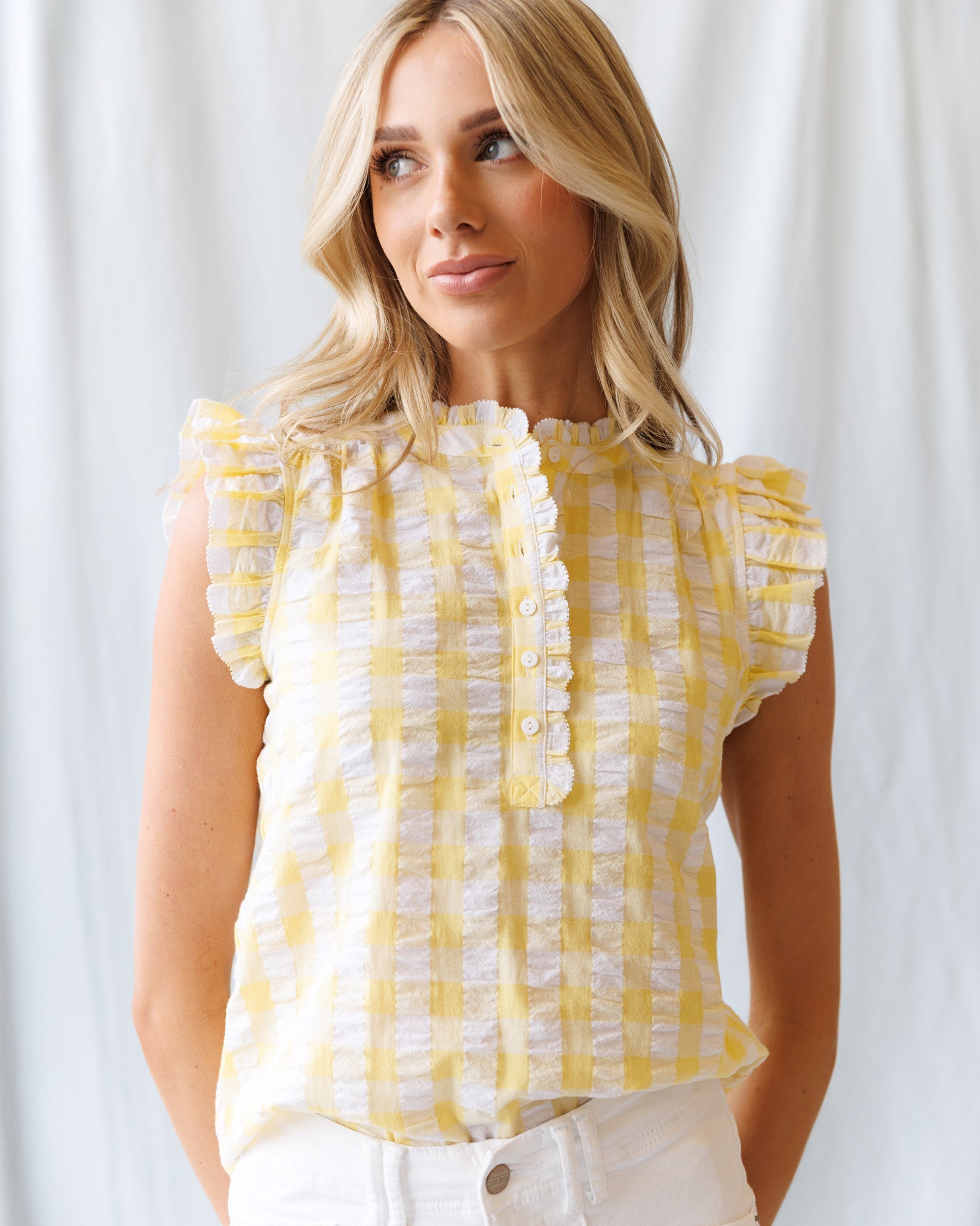 Woman wearing a yellow checkered blouse against a white background