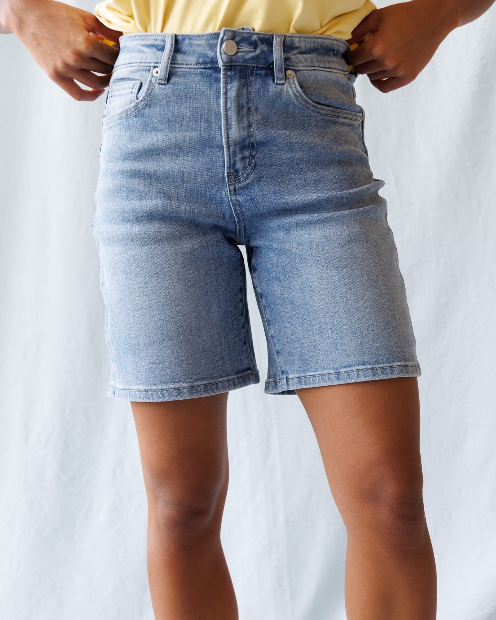 Person wearing light blue denim shorts on a plain background