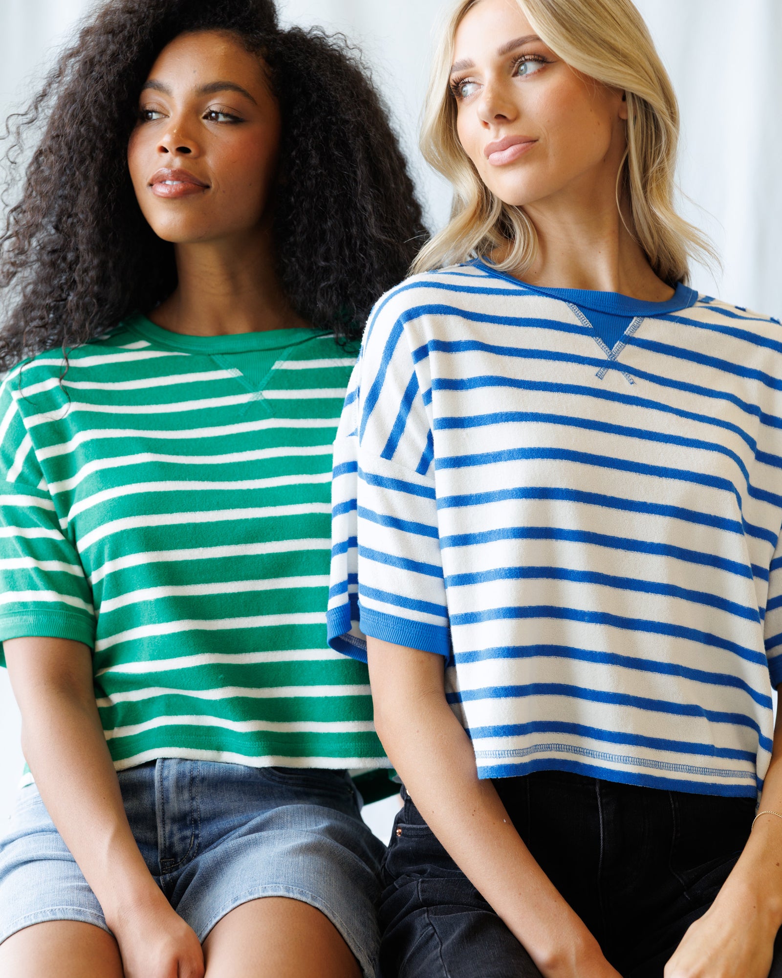 Two women wearing striped shirts sitting side by side.