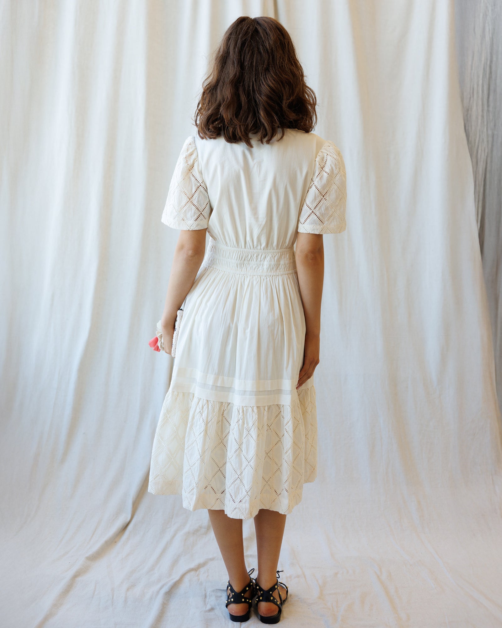 Woman wearing a white dress with a textured pattern against a plain background