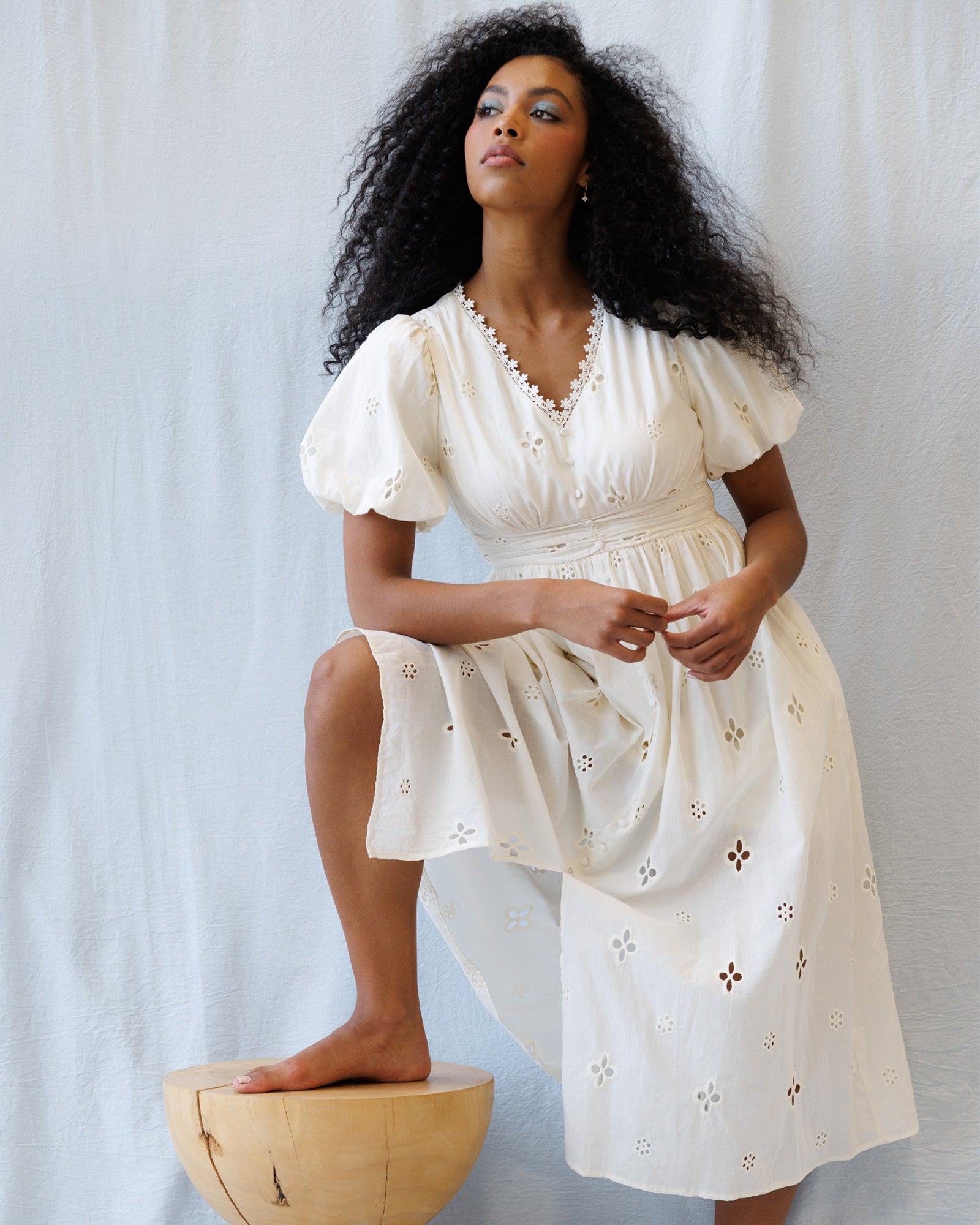 Woman wearing a white dress with floral embroidery against a light background
